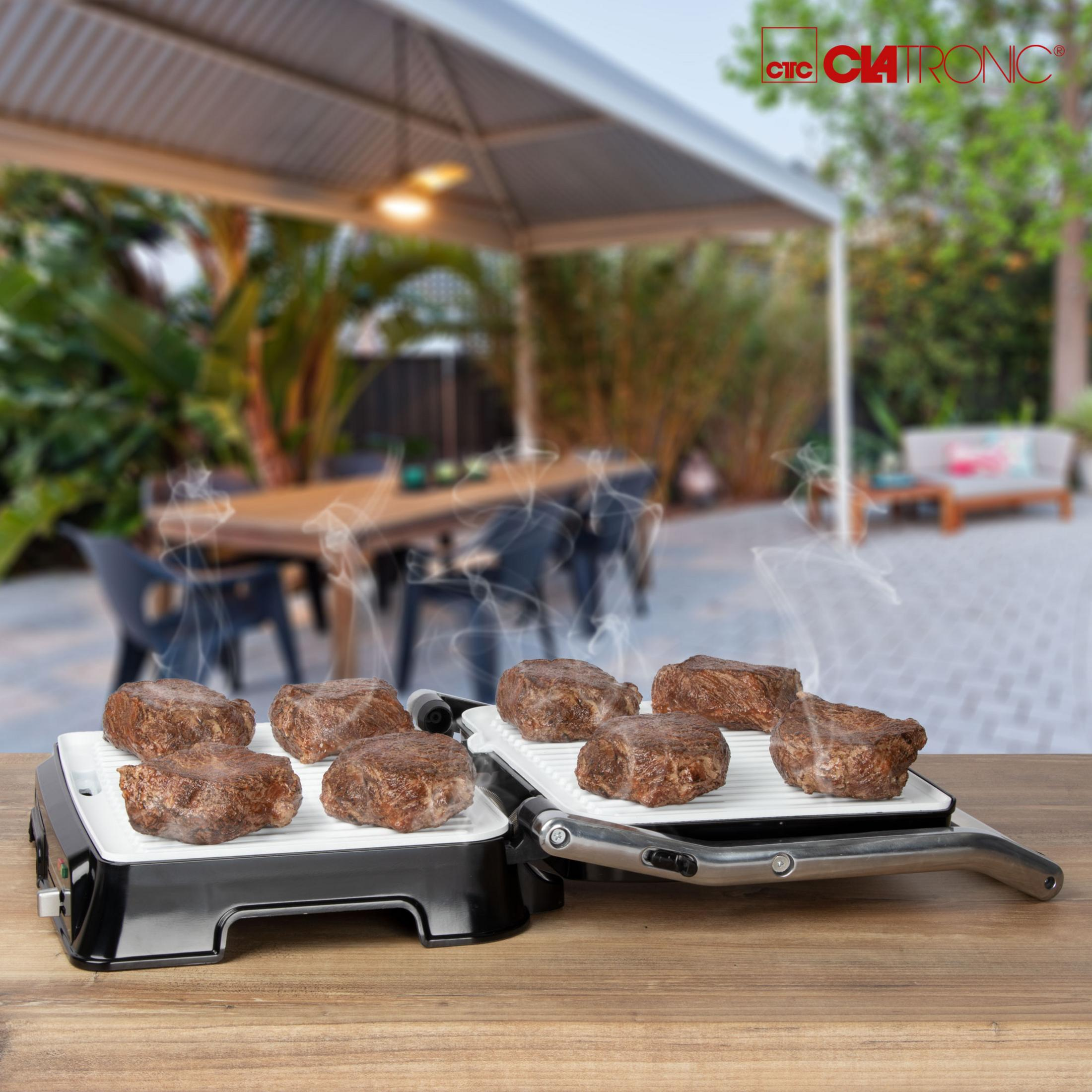 Grill z ugotowanym mięsem. Para się unosi. Ustawienia patio z ludźmi w tle.