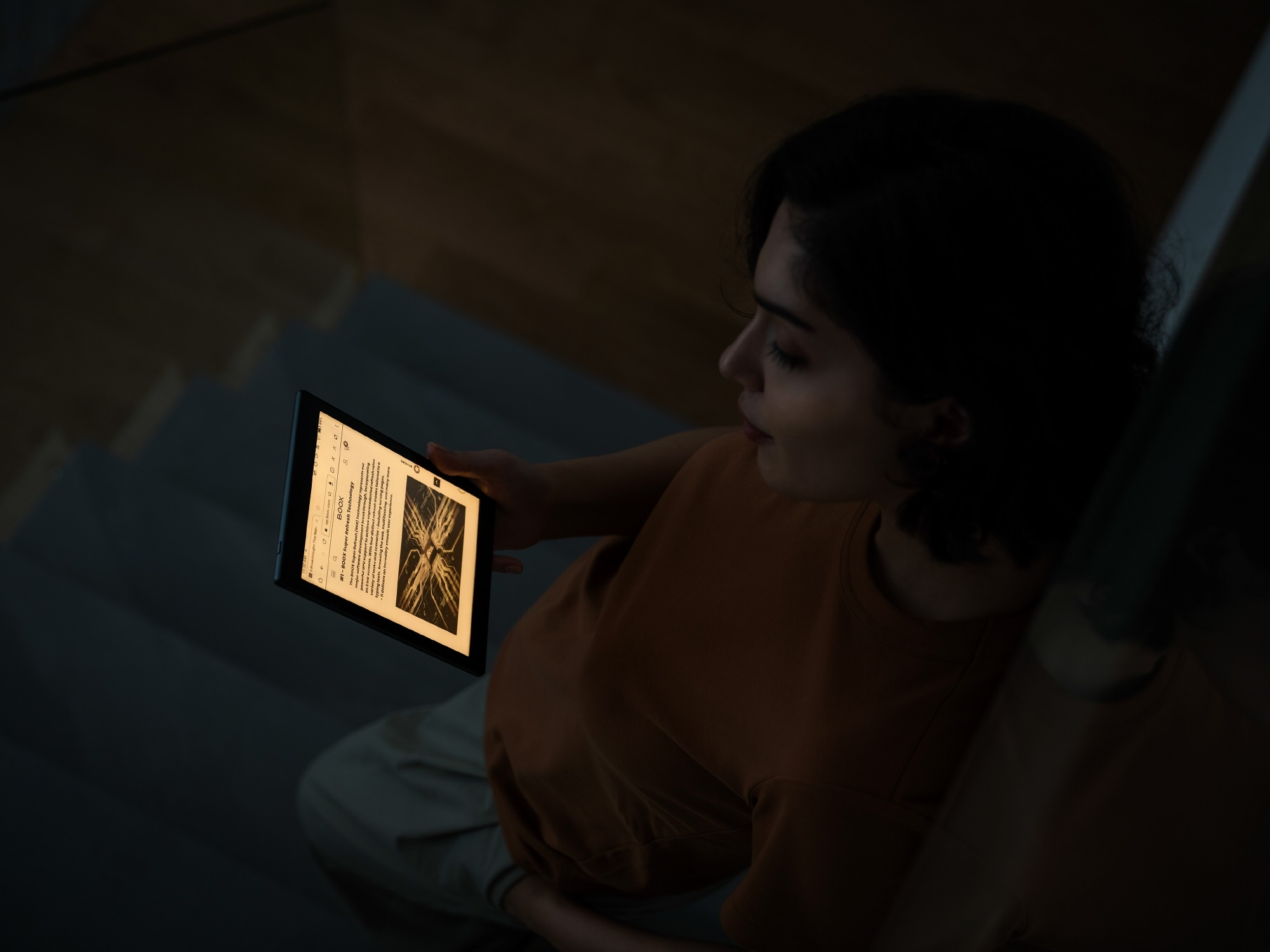 Eine Frau, die nachts ein Tablet liest. Das Tablet ist beleuchtet, die Szene ist dunkel.