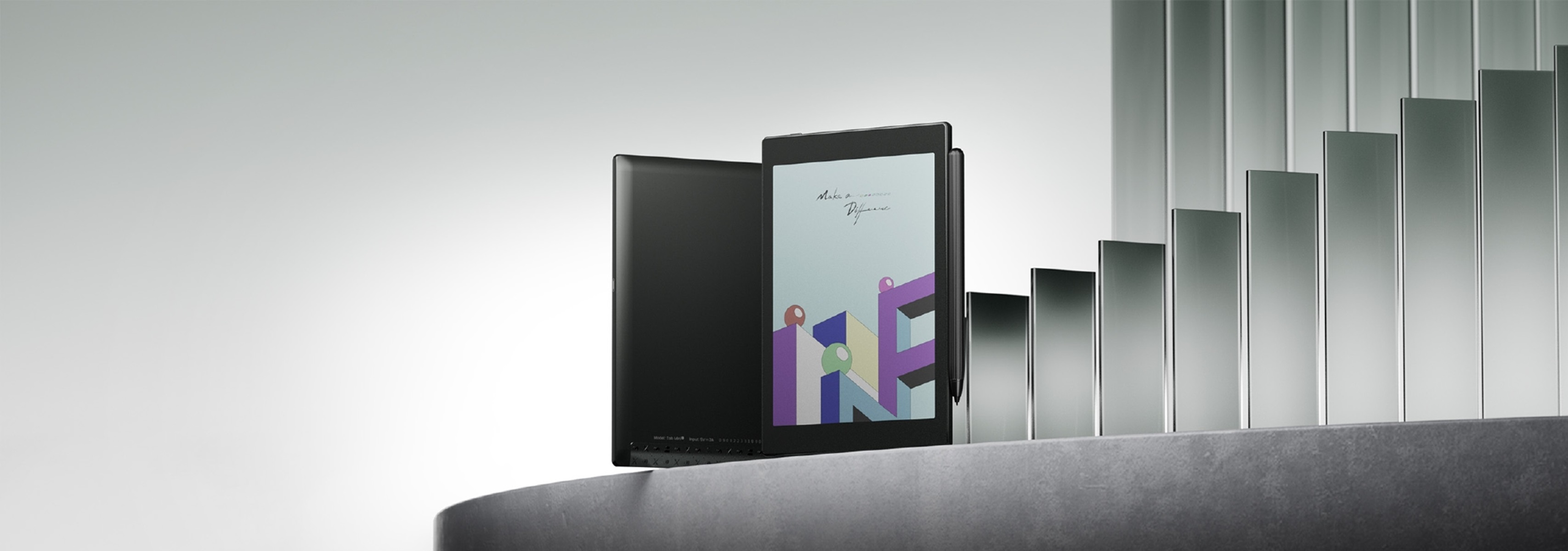 Schwarzes Tablet mit Stift, geöffnet, und Notizbuchseite, auf silberner Oberfläche.