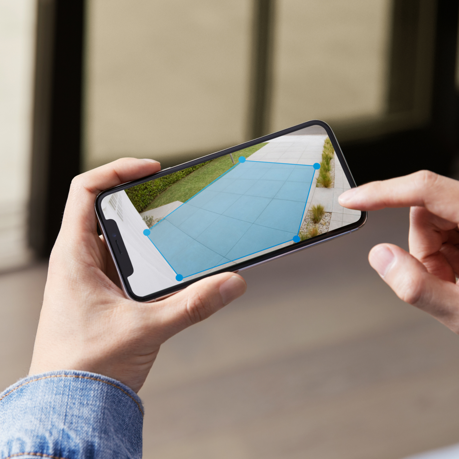 Osoba trzymająca smartfon pokazujący widok z kamery bezpieczeństwa.