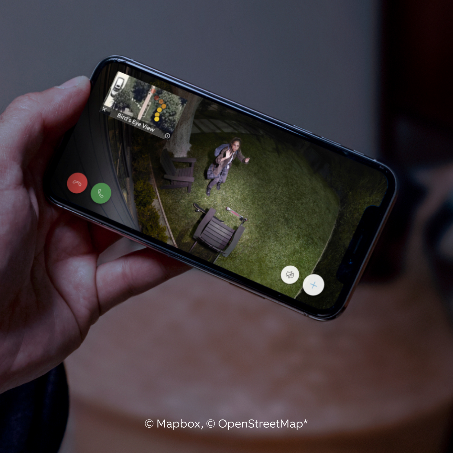 Dłoń trzymająca telefon pokazujący osobę na podwórku w nocy.