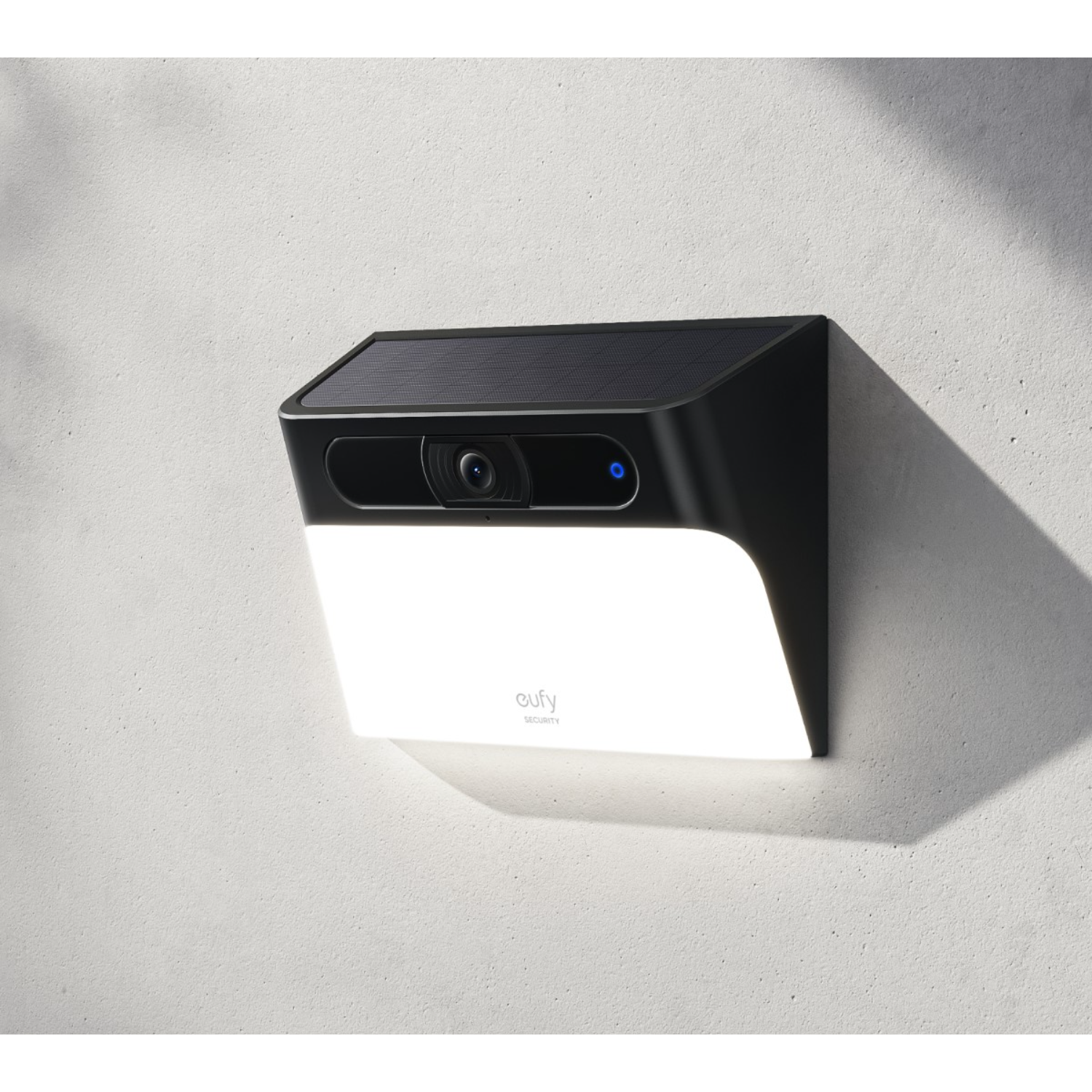 Czarna kamera bezpieczeństwa eufy na białej ścianie, panel słoneczny i jasna dioda LED.