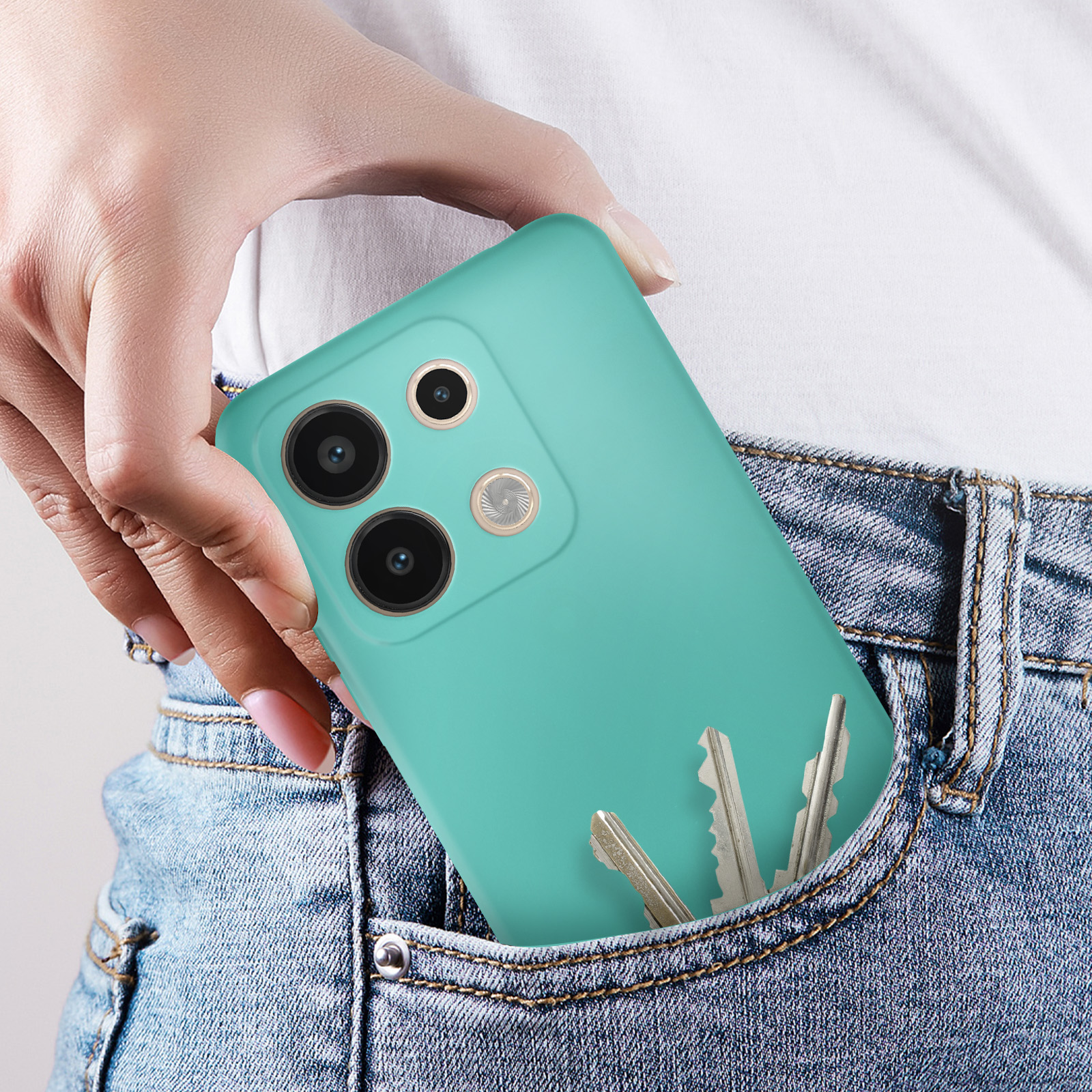 Mano che tiene un telefono verde acqua in tasca di jeans, chiavi visibili.