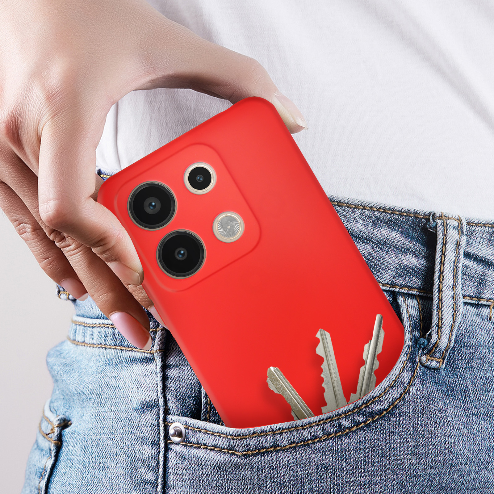 Una mano che tiene un telefono rosso in tasca. Le chiavi sono visibili nella tasca.