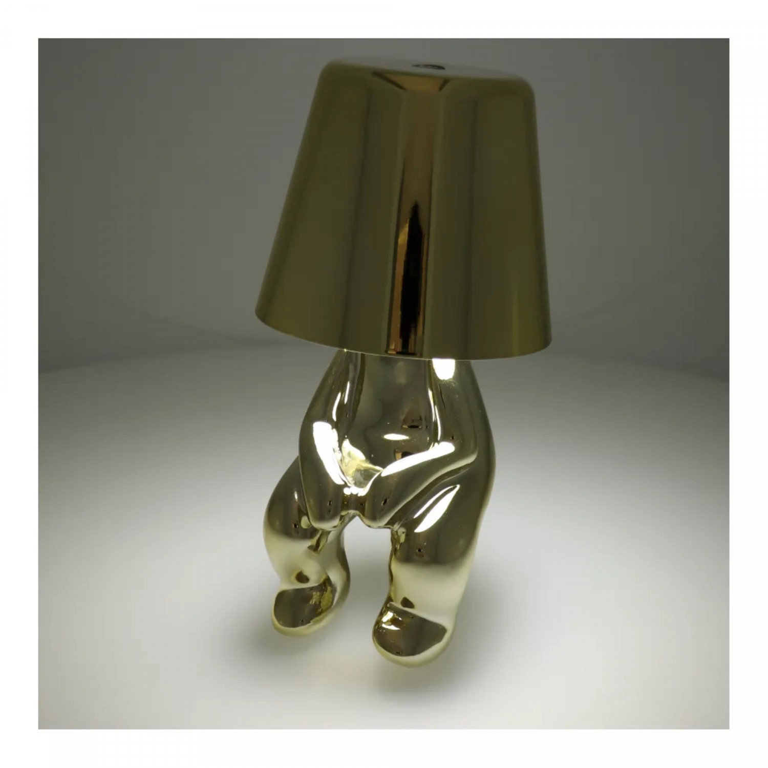 Eine goldene Lampe in menschenähnlicher Form, mit einem Lampenschirm, der die Glühbirne bedeckt.