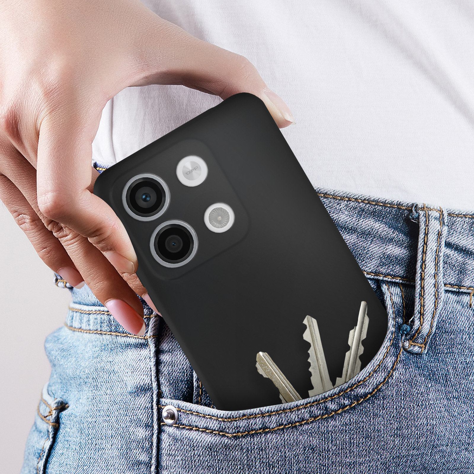 Una mano che tiene una custodia nera per telefono con chiavi nella tasca dei jeans blu.