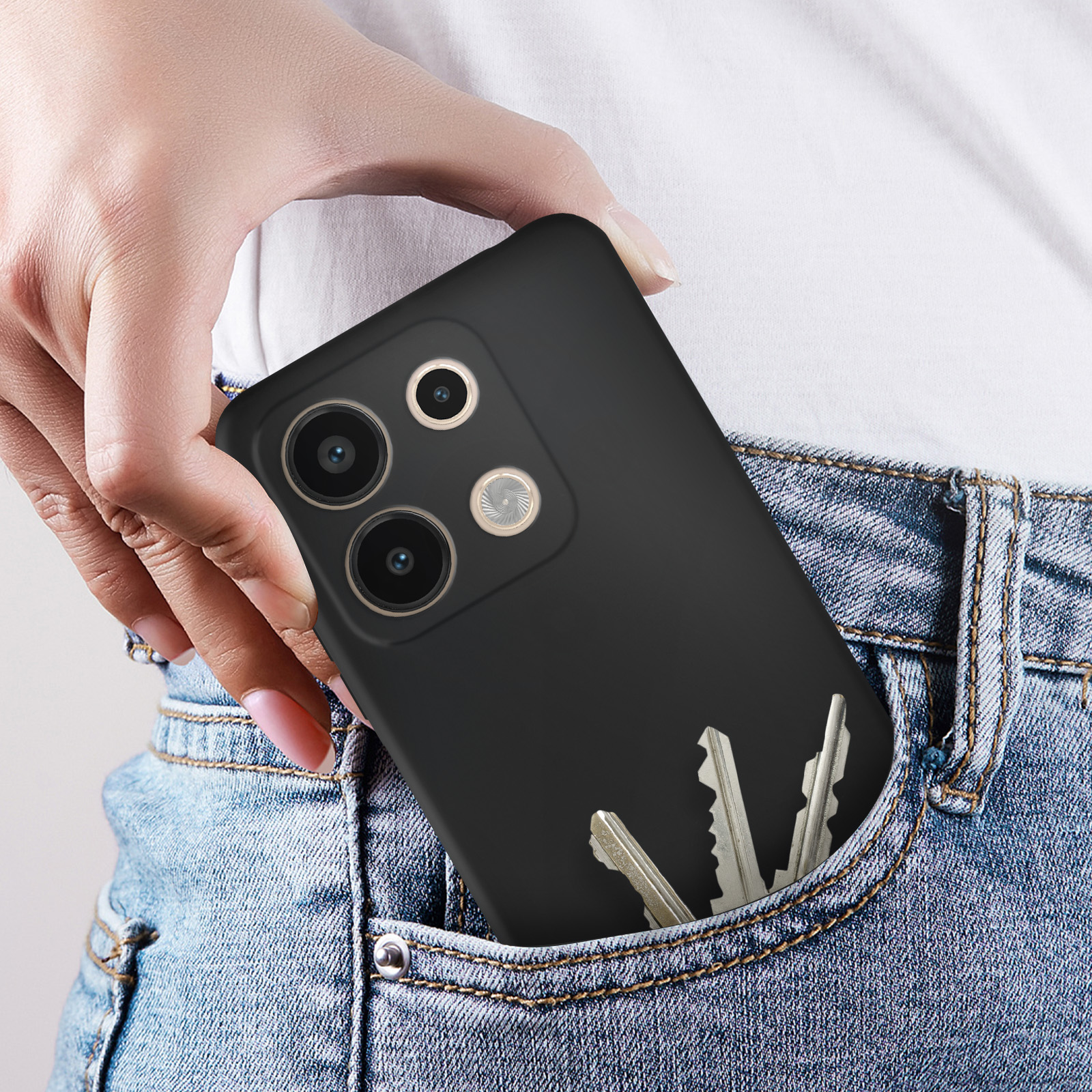 Mano in tasca dei jeans con telefono nero e tre chiavi.