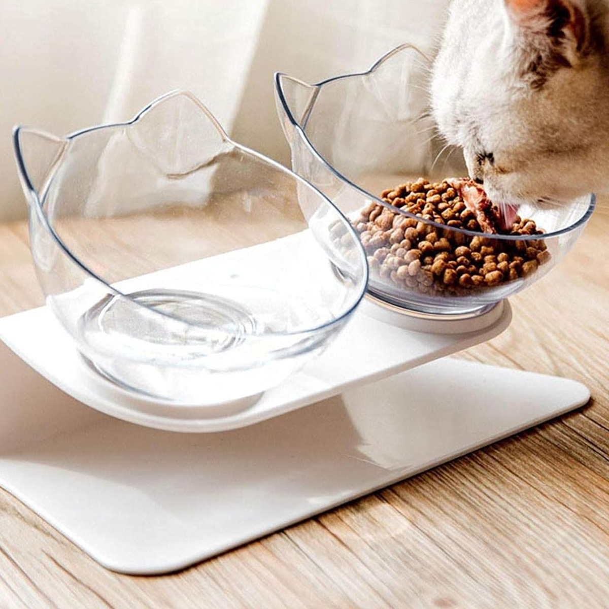 Katze, die aus einer katzenförmigen Schüssel isst, die auf einem weißen Ständer steht.