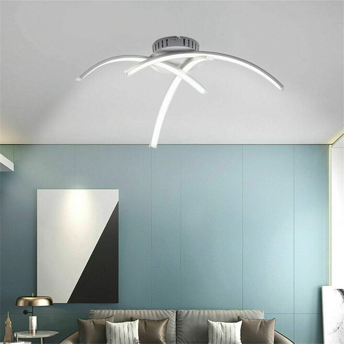 Moderne Deckenleuchte mit geschwungenen weißen Armen vor blauer Wand.