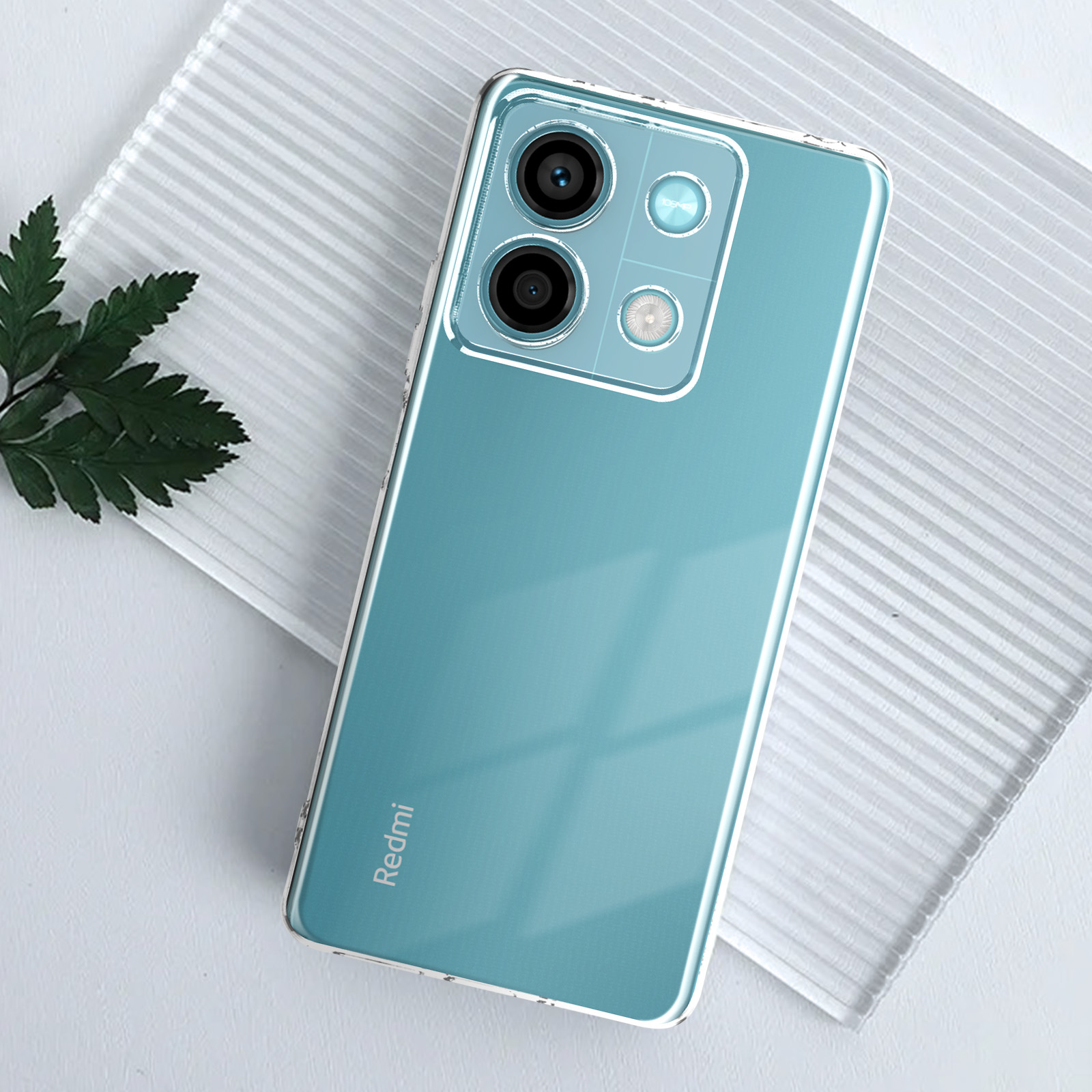 Telefono blu con custodia trasparente, due fotocamere e pianta verde. Sfondo bianco.
