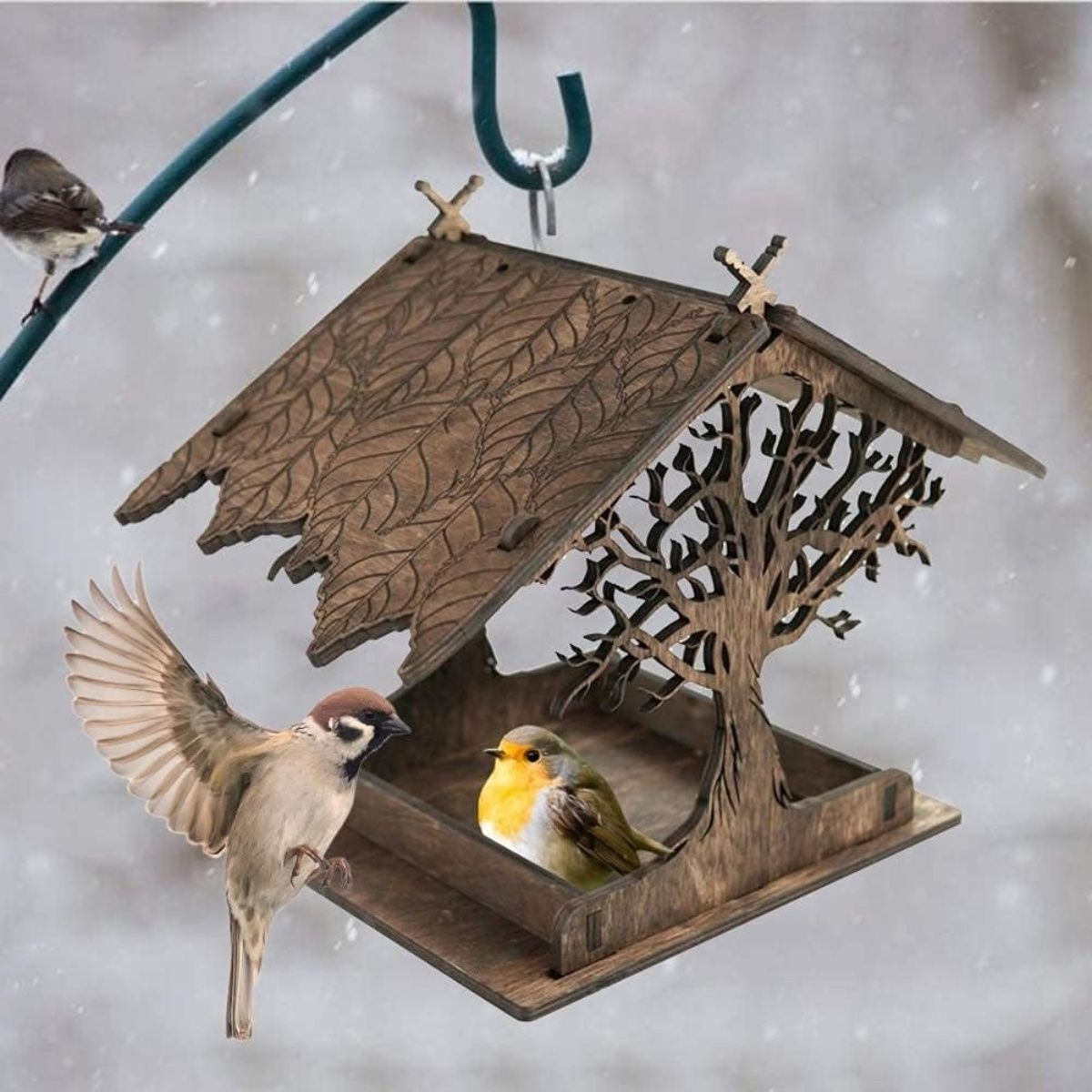 Vogelfutterhaus aus Holz mit Vögeln, darunter ein Spatz und ein Rotkehlchen, vor Schnee.