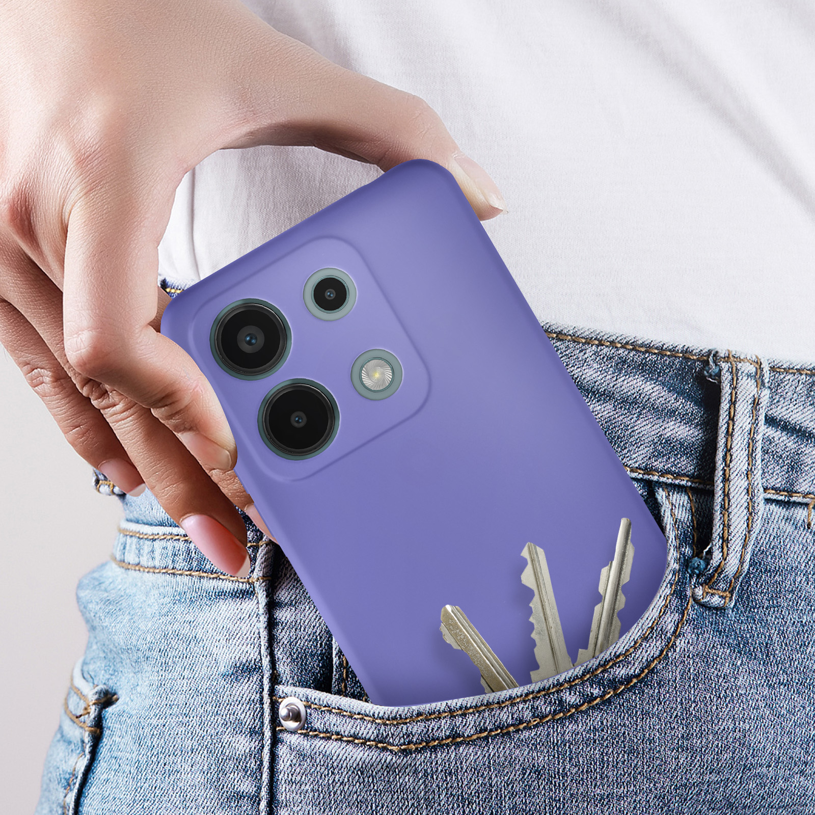 Mano che tiene un telefono viola in una tasca di jeans, con chiavi visibili.