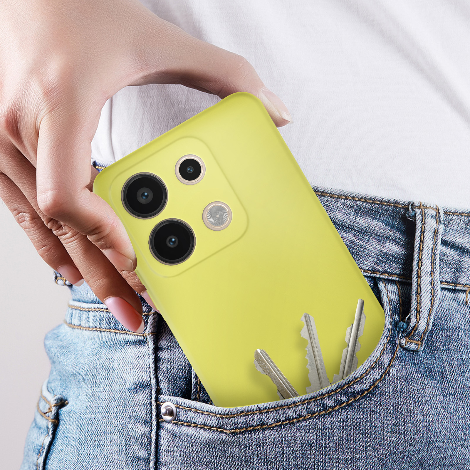 Una mano mette un telefono giallo in una tasca di jeans con chiavi. Ha telecamere.