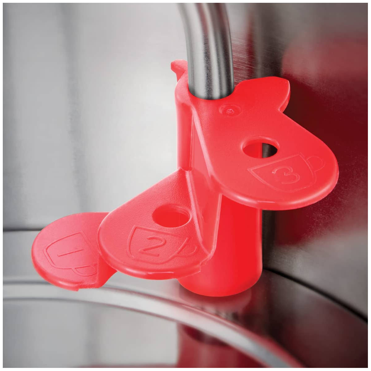 Roter Messbecher mit drei Tassenanzeigen, Metallgriff, Nahaufnahme.