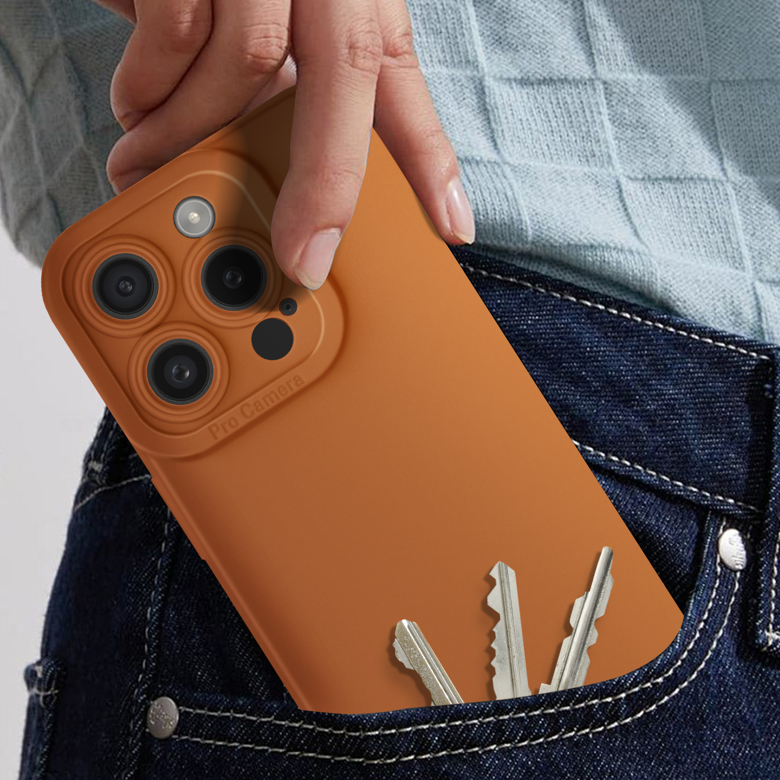 Mano che tiene un telefono in una custodia marrone. Chiavi nella tasca dei jeans.