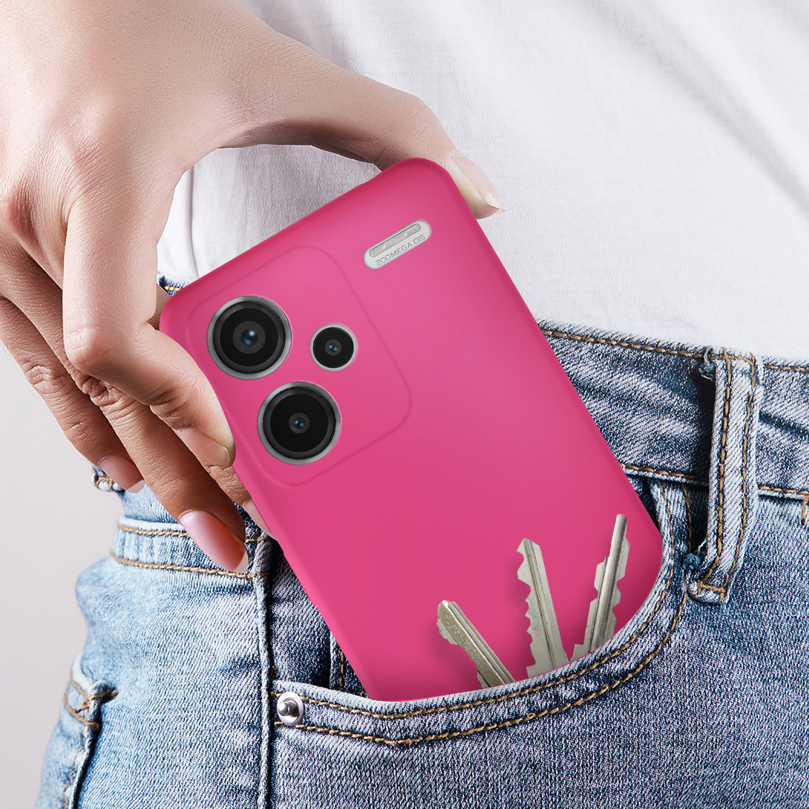 Mano che tiene un telefono rosa in una tasca dei jeans con chiavi.