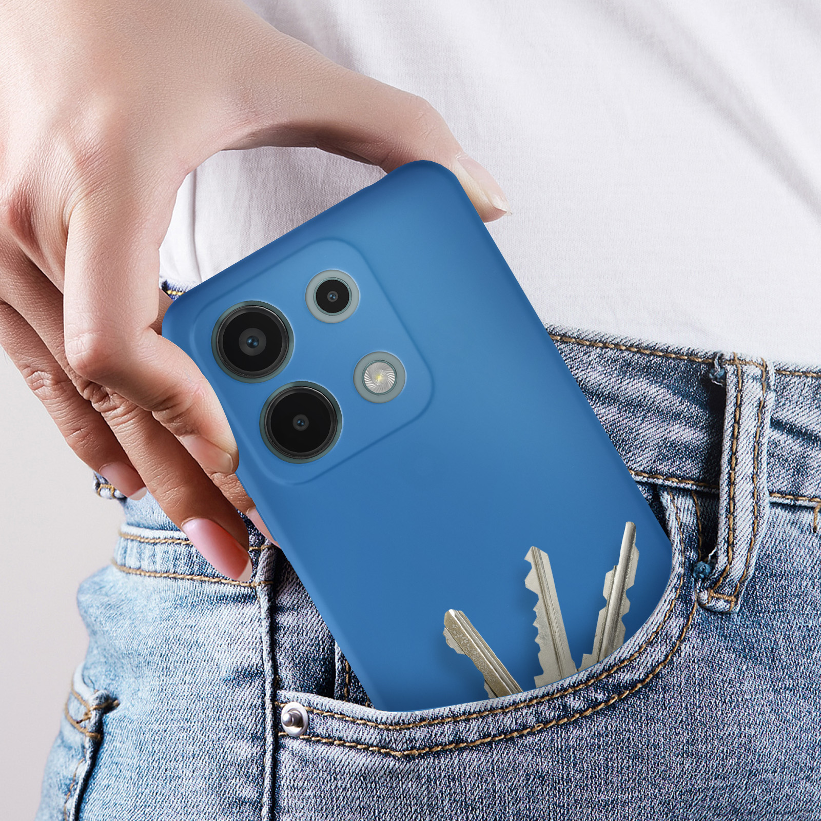 Mano che tiene un telefono blu in tasca. Chiavi d'argento in tasca.
