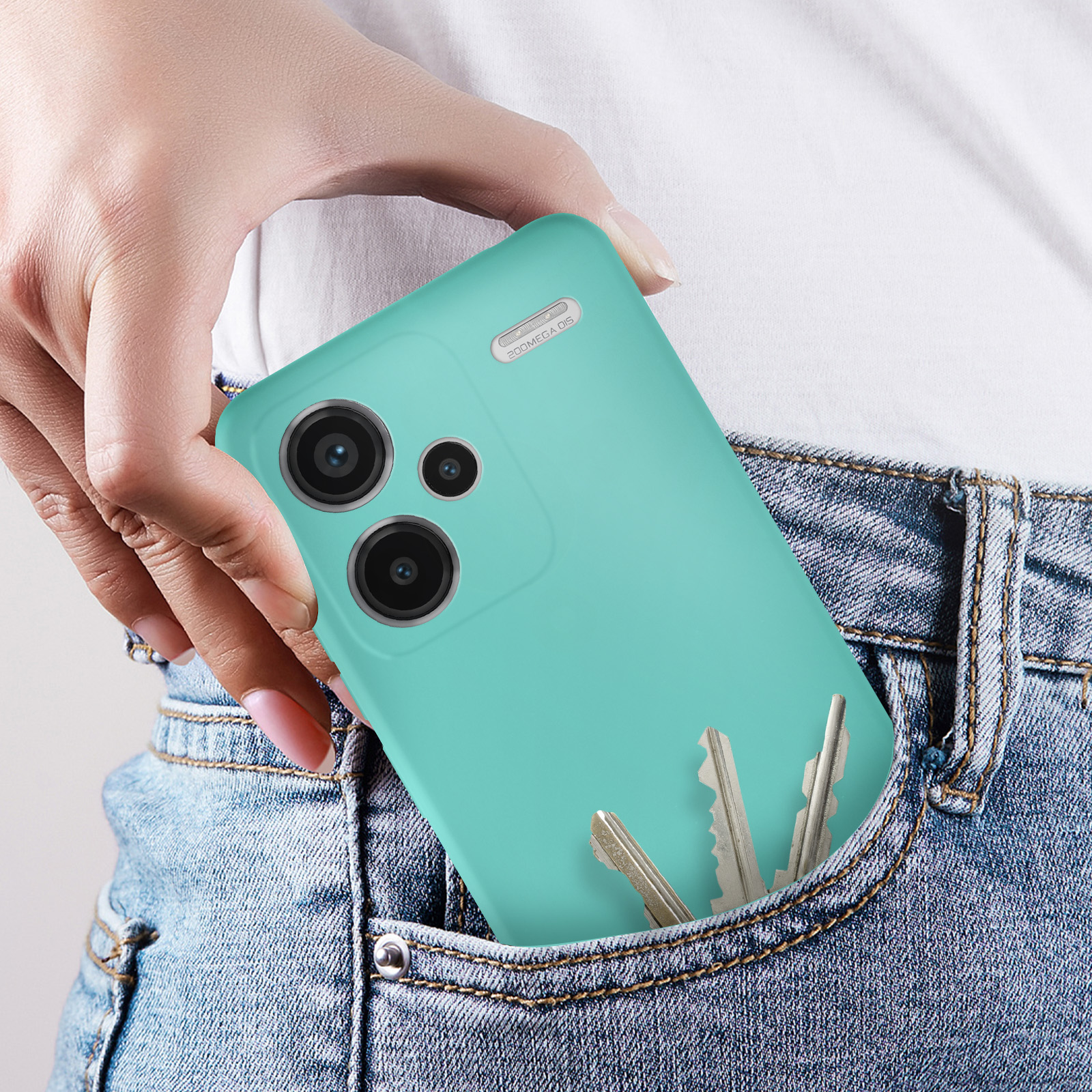 Una mano che tiene uno smartphone verde acqua in una tasca di jeans con chiavi.