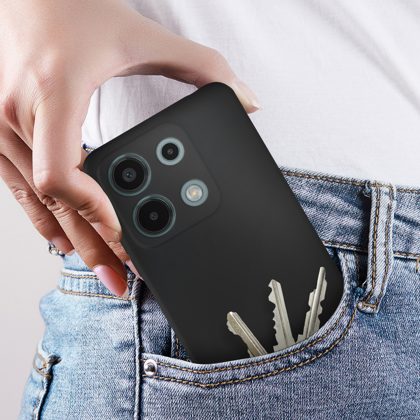 Una mano che tira fuori un telefono nero da una tasca di jeans. Le chiavi sono visibili anche nella tasca.