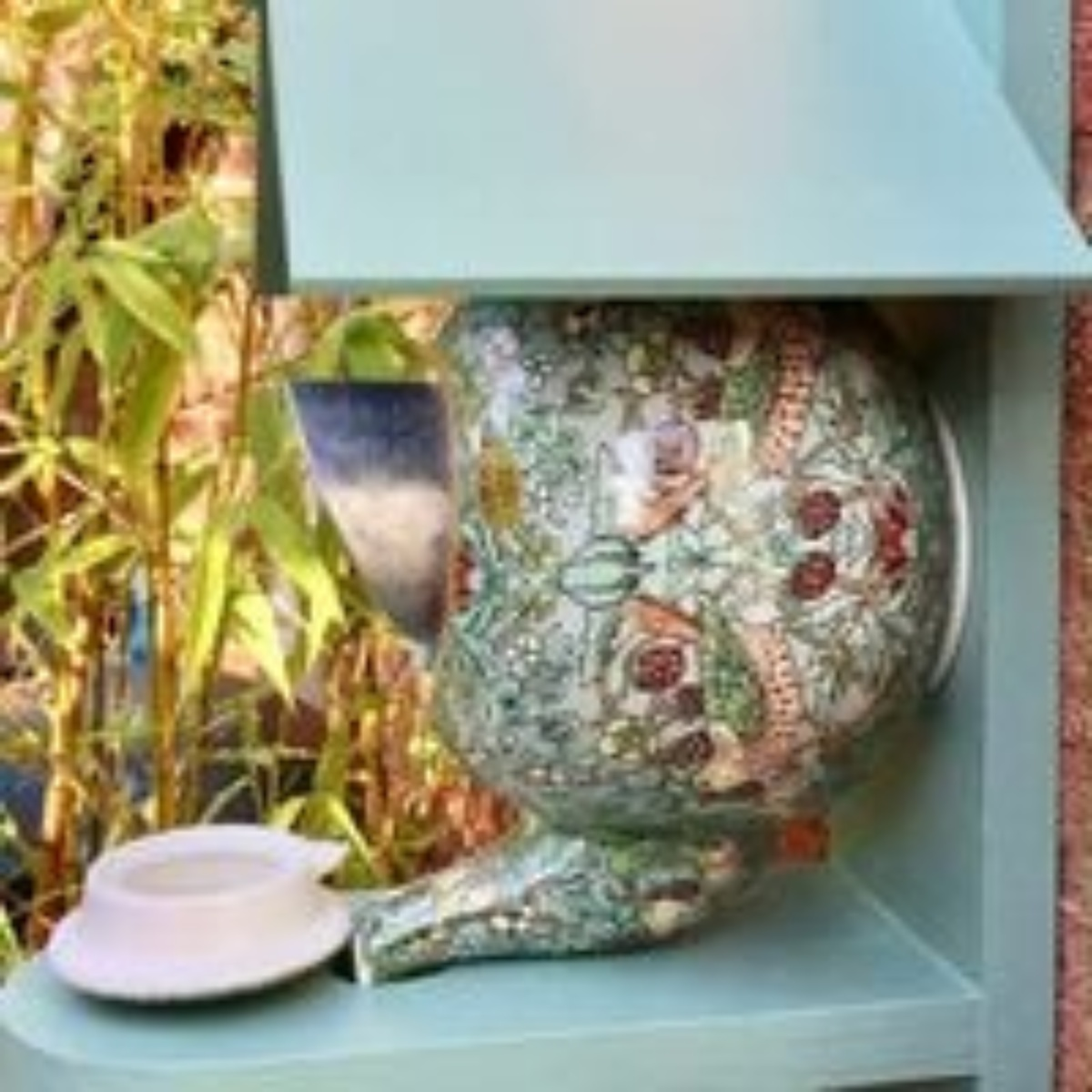 Vogelfutterhaus mit ornamentalem Blumendesign, montiert auf hellblauer Struktur.