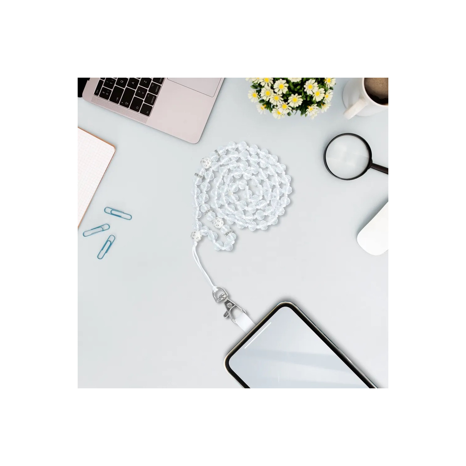 Configurazione scrivania con laptop, telefono, blocco note e accessori. Sfondo bianco.