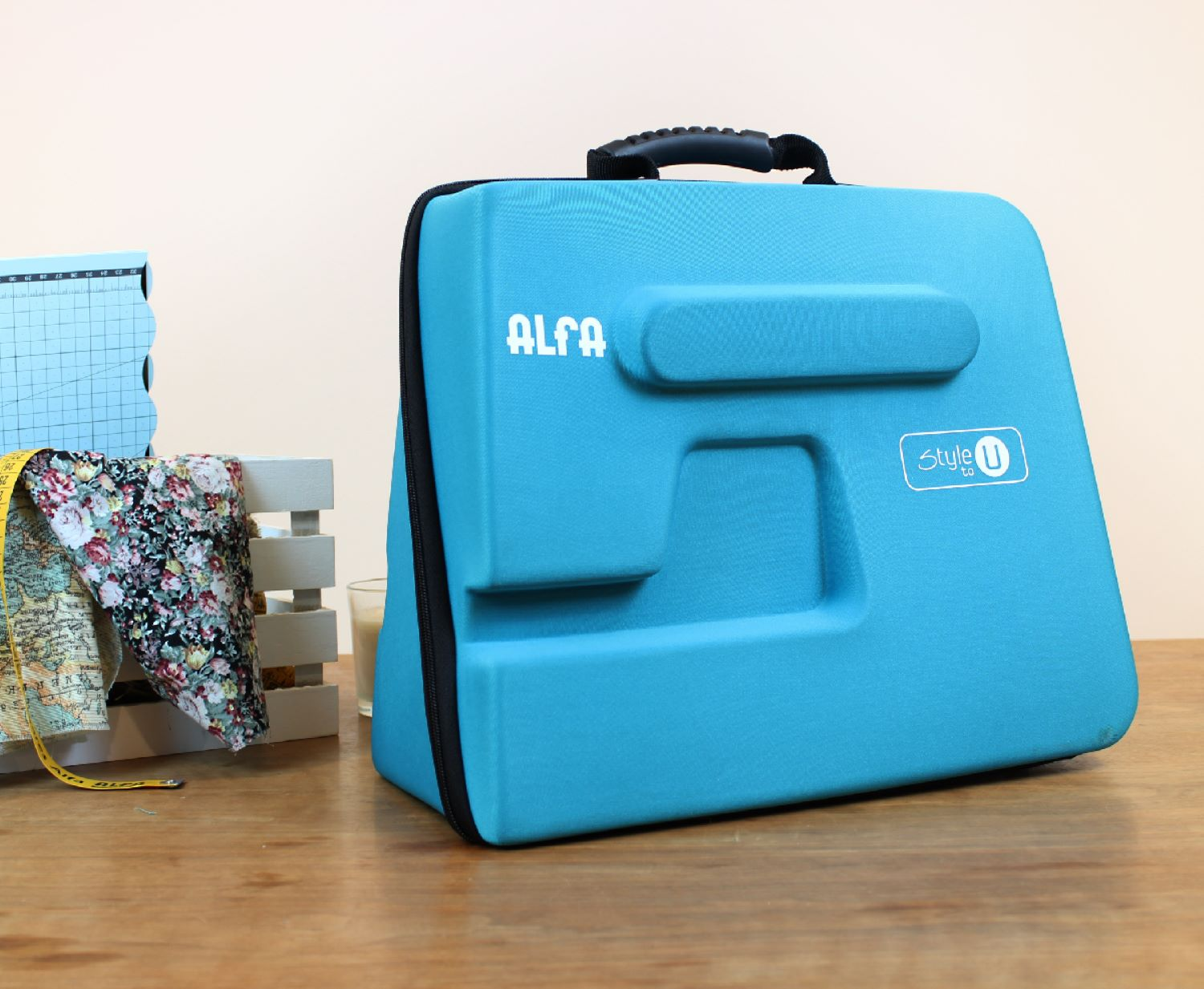 Funda azul de máquina de coser, con tela y cinta métrica cerca.