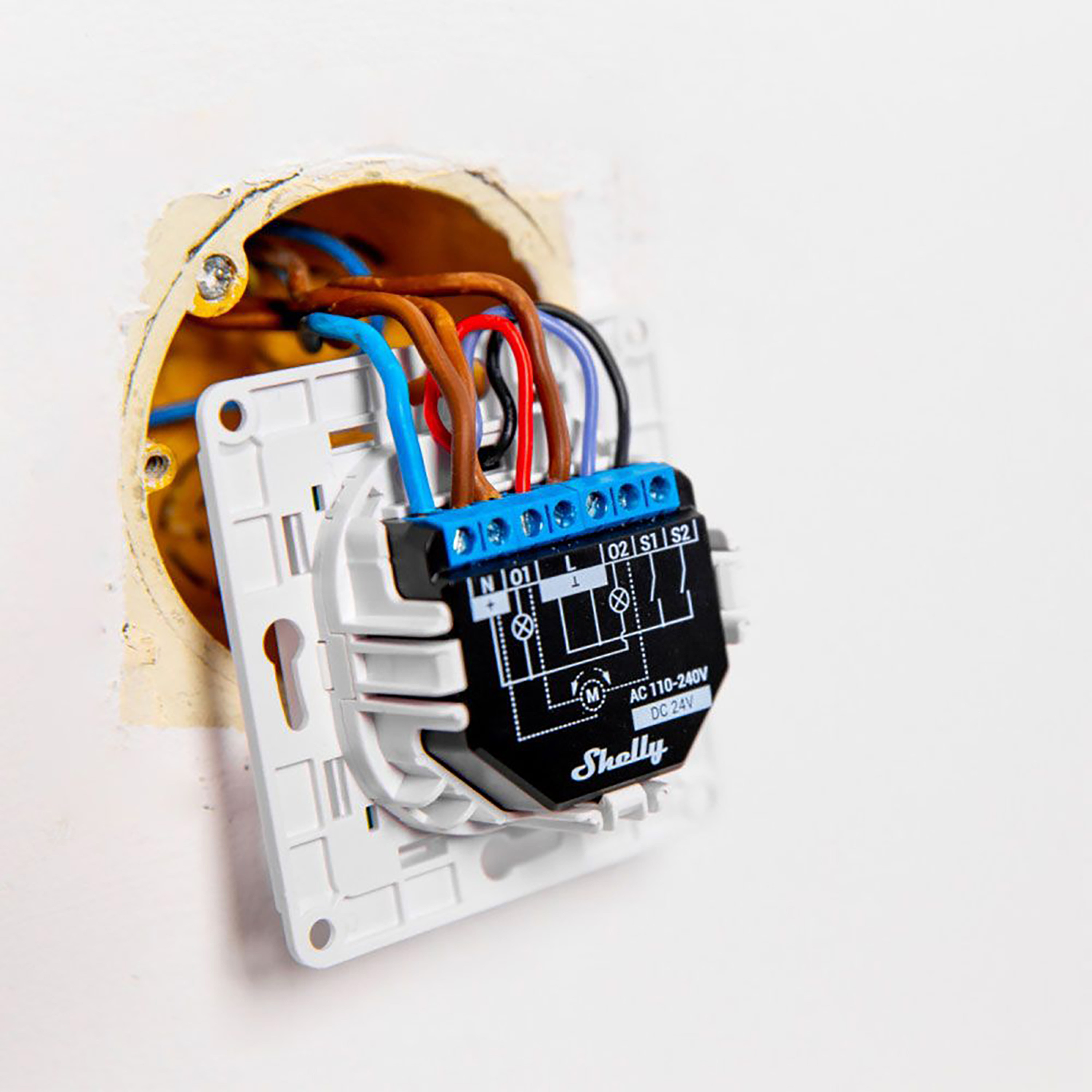Una presa elettrica bianca con dispositivo Shelly Smart Home installato, fili visibili.