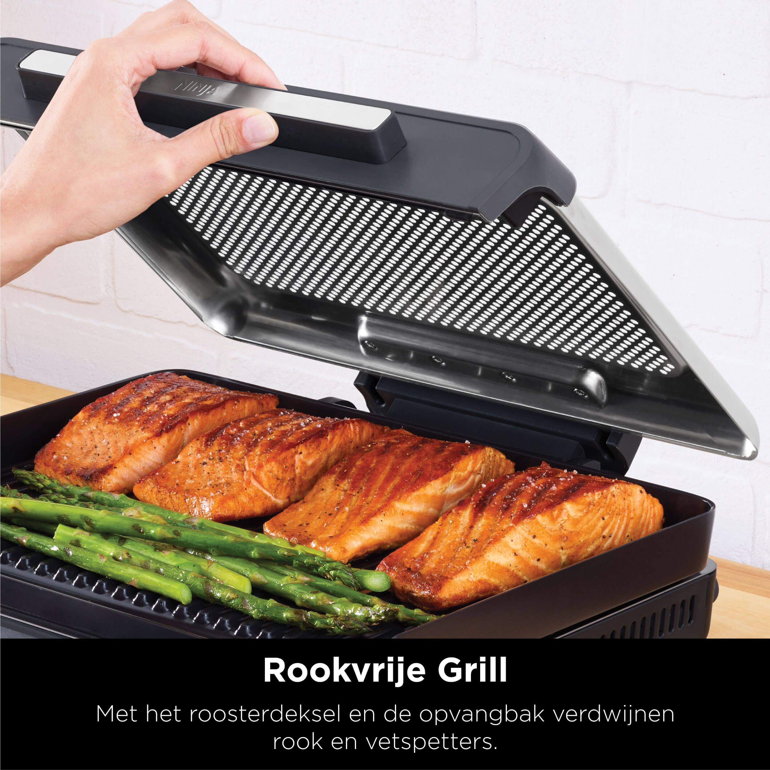 A hand opening a grill. Grilled salmon and asparagus are visible inside the grill.
