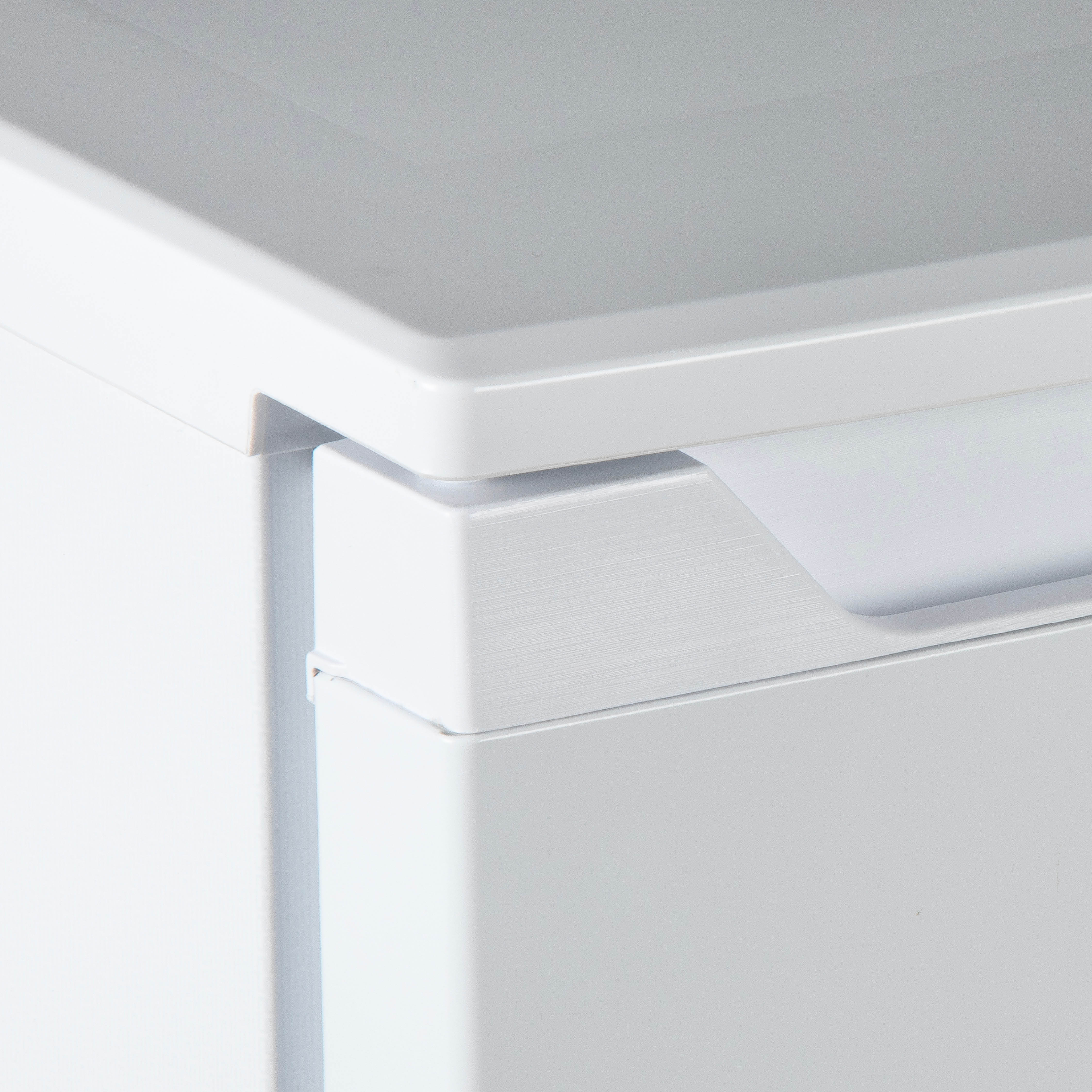 Close-up view of a white refrigerator handle, showing the edge of the appliance.