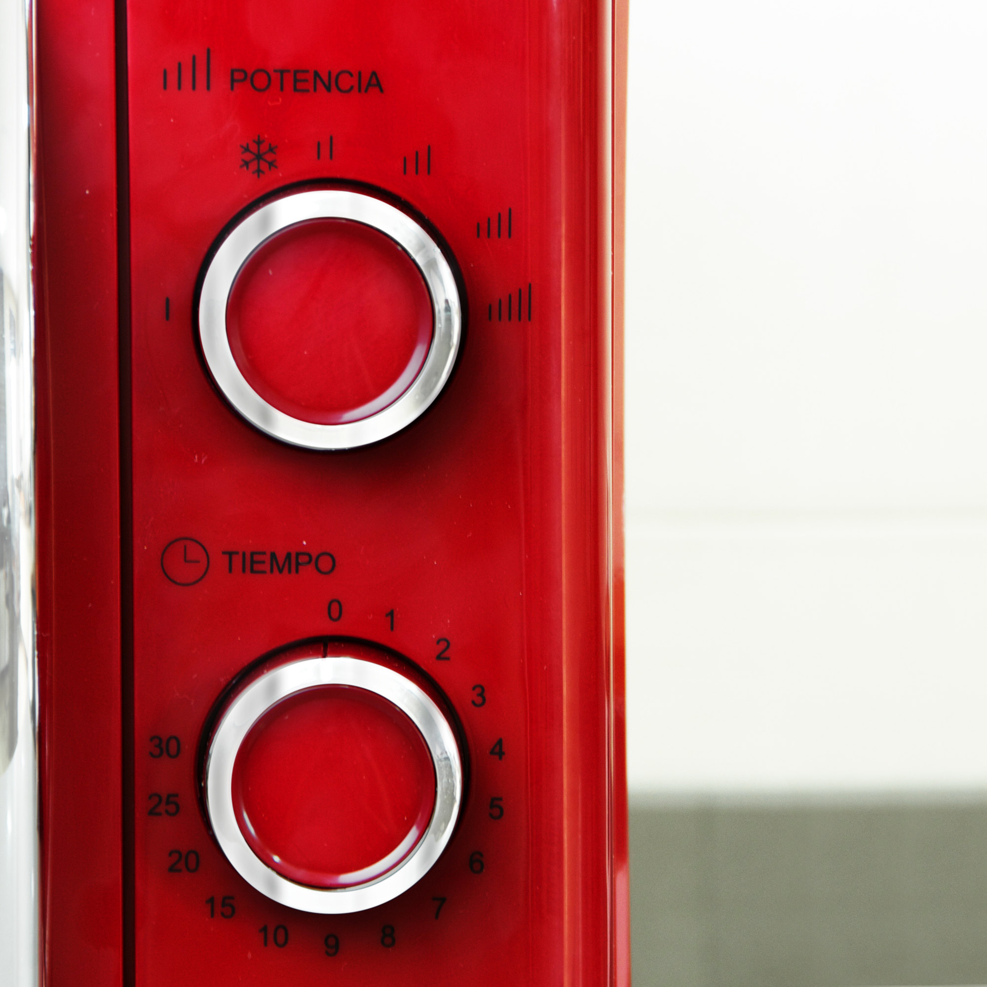 Panel de control de microondas rojo con dos diales y textos, sobre fondo blanco.