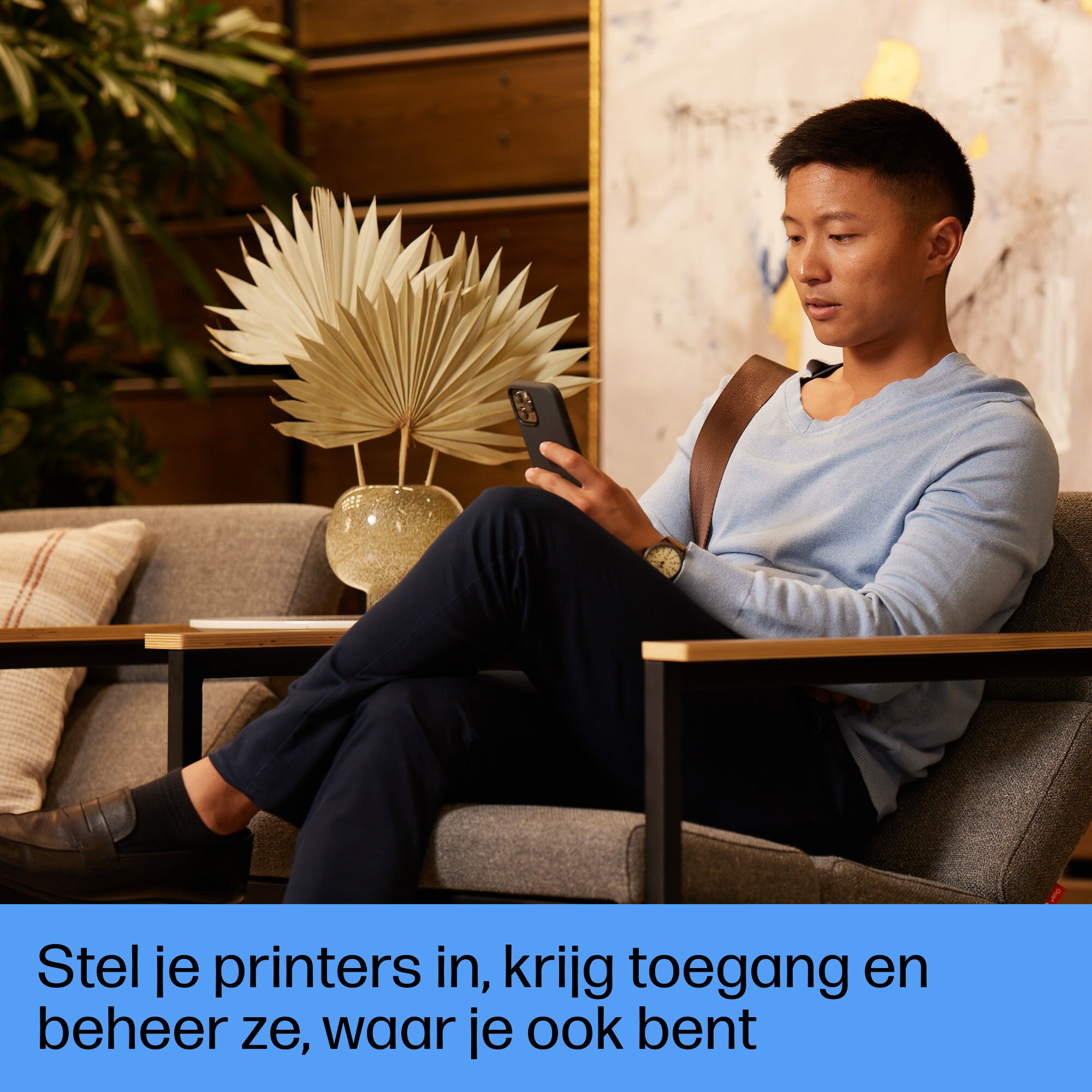 Mężczyzna siedzi na sofie, patrząc na swój telefon. Tekst wyświetlany jest na dole.