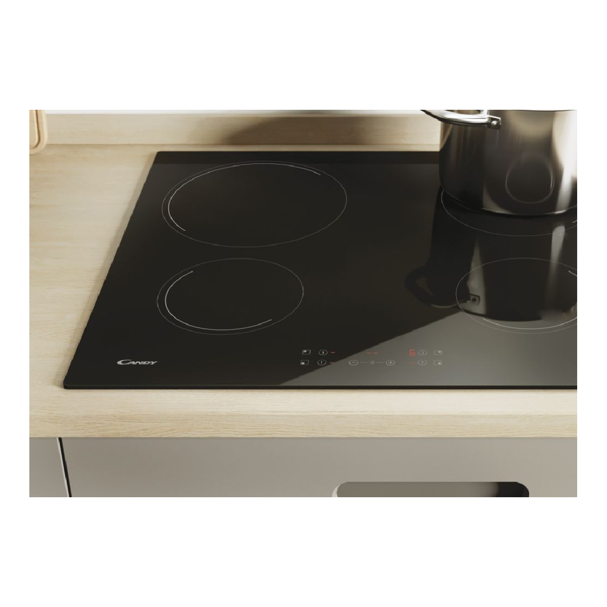 Czarna płyta indukcyjna Candy ze srebrnym garnkiem. Widoczne są cztery strefy gotowania.