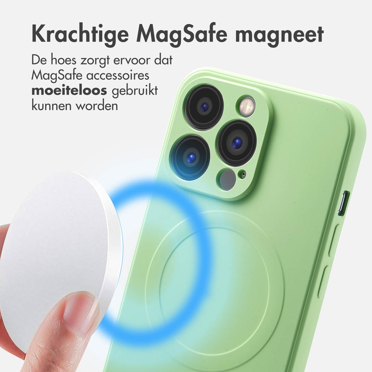 Een hand houdt een witte MagSafe-accessoire vast in de buurt van een groene telefoonhoes. Blauwe ring geeft magnetische verbinding aan.