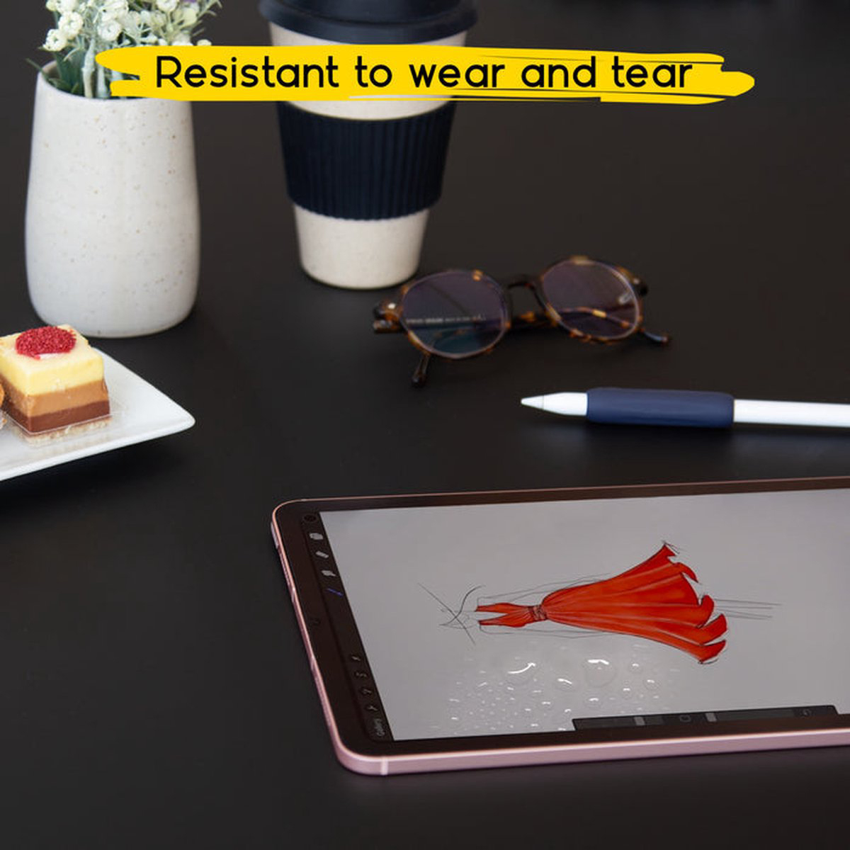 Un tablet con un design di abito e altri elementi su un tavolo nero. Testo: 'Resistente all'usura'.