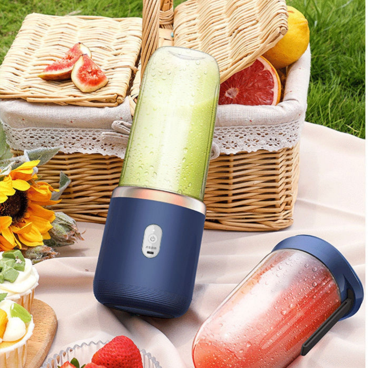 Tragbarer Mixer mit blauem Sockel, Obstkorb und zweitem Mixer mit roter Flüssigkeit.