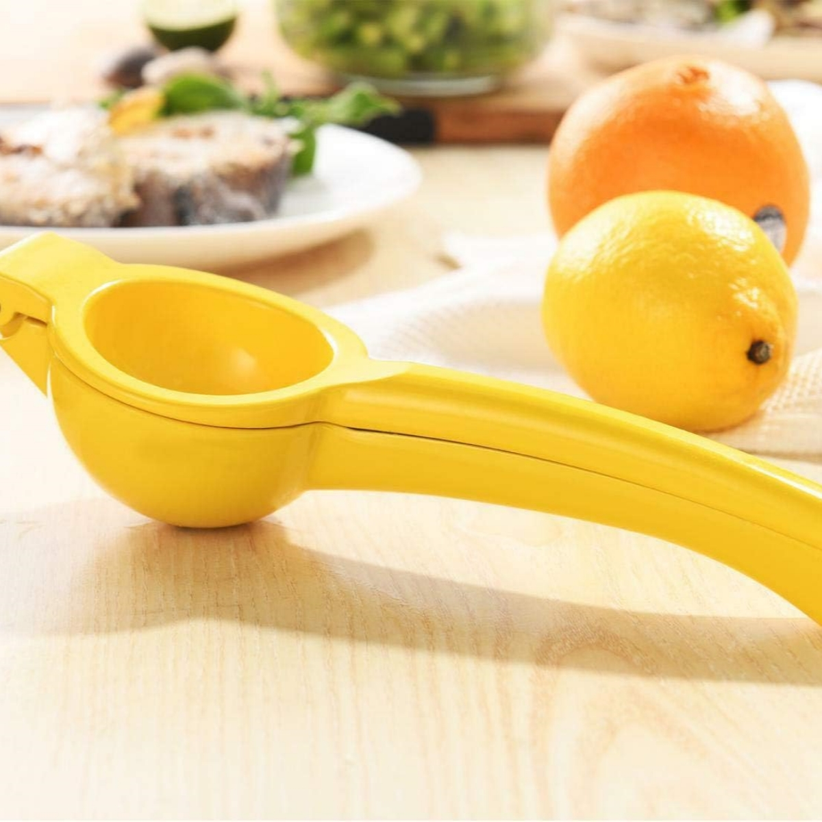 Ein gelber Zitronenentsafter steht auf einer Holzoberfläche mit Zitronen, Orangen und anderen Früchten.