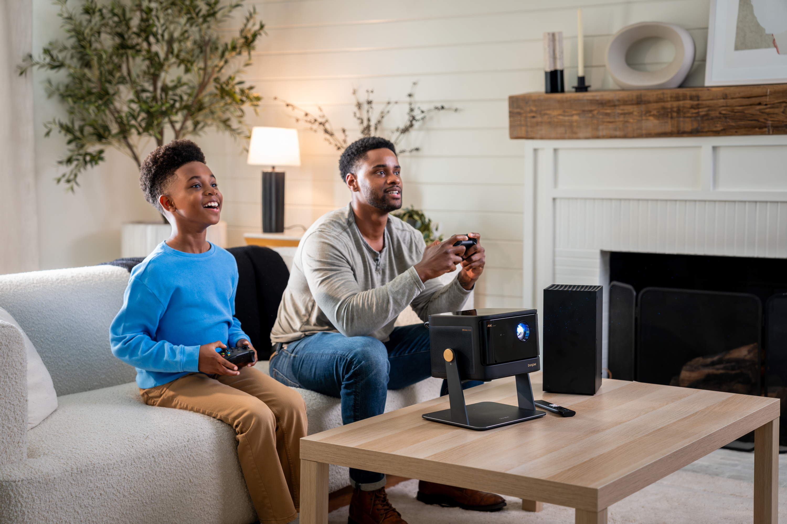 Ojciec i syn grający w gry wideo, z projektorem i małym stolikiem.