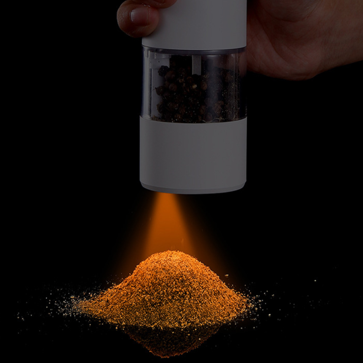 Pfeffermühle gibt orangefarbenen Pfeffer auf einen Haufen frei.