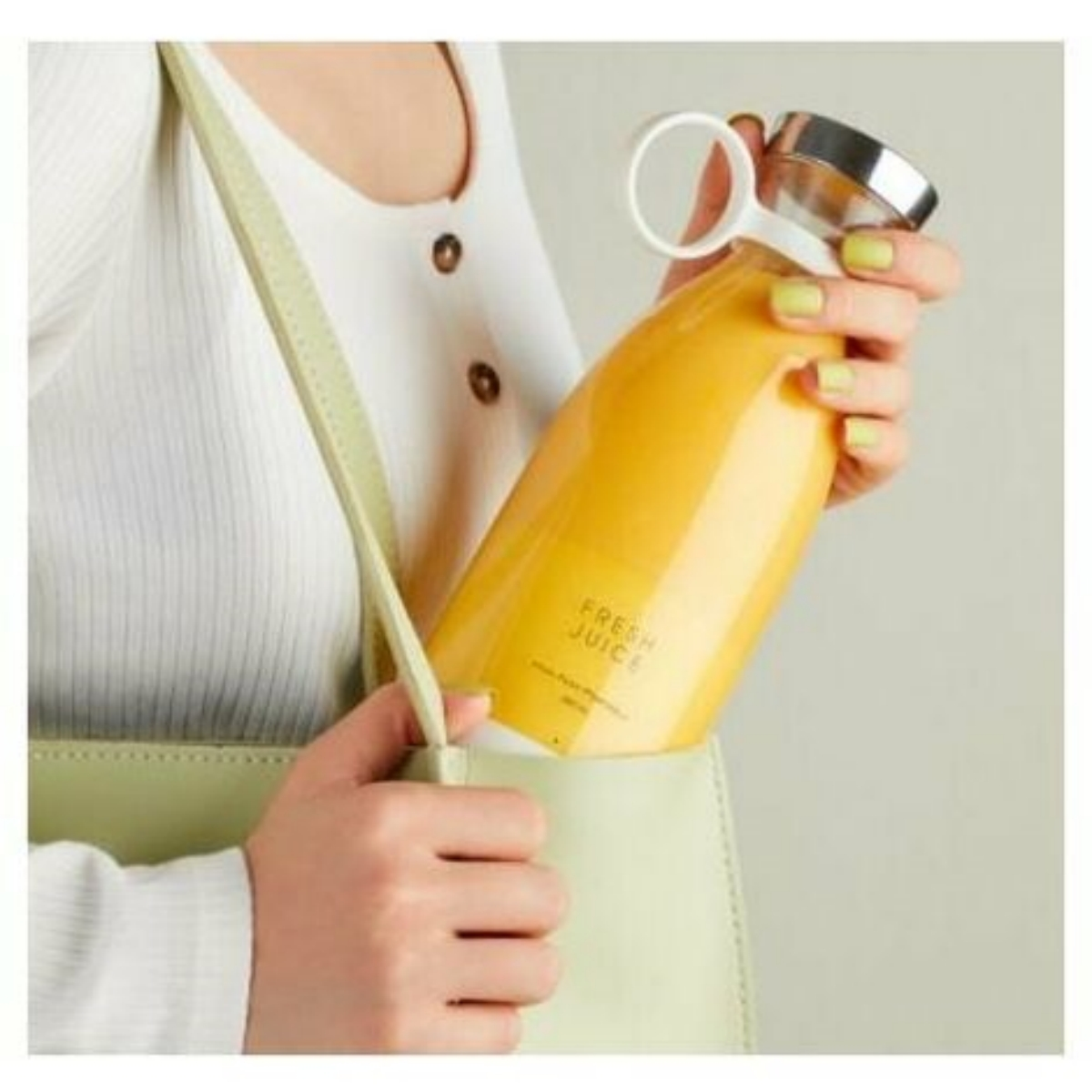 Eine Frau hält eine Flasche Saft in einer hellgrünen Tasche.