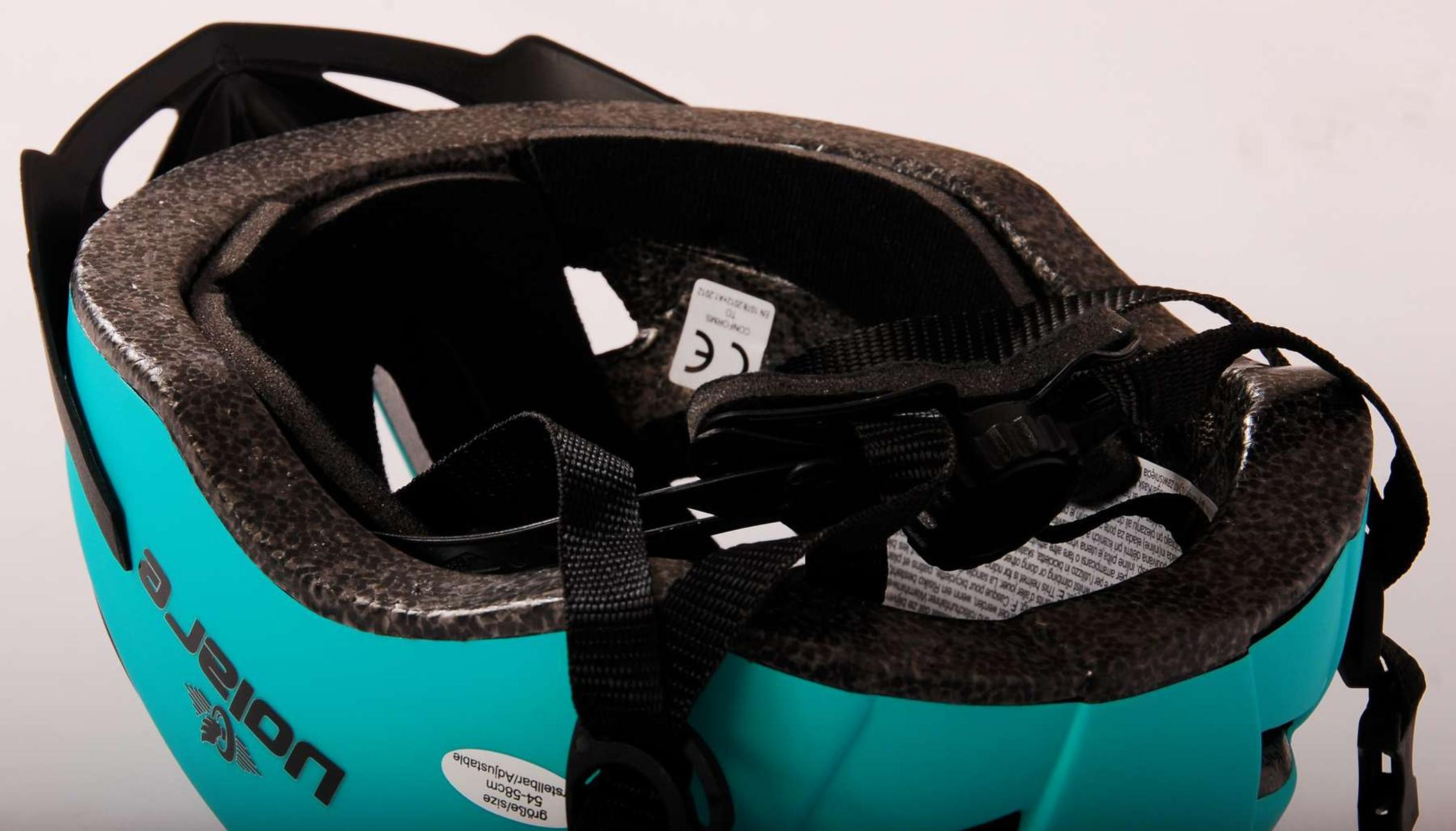 Innenseite eines türkis-schwarzen Kinderhelms mit Riemen und Schaumstoffpolsterung.