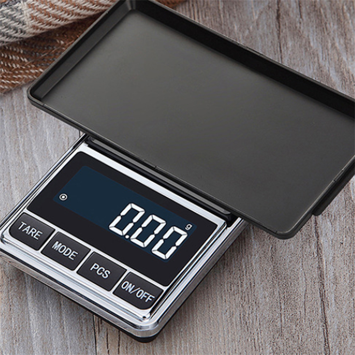 Digitalwaage mit offenem Deckel. Das Display zeigt 0,00. Sie liegt auf einer Holzoberfläche.