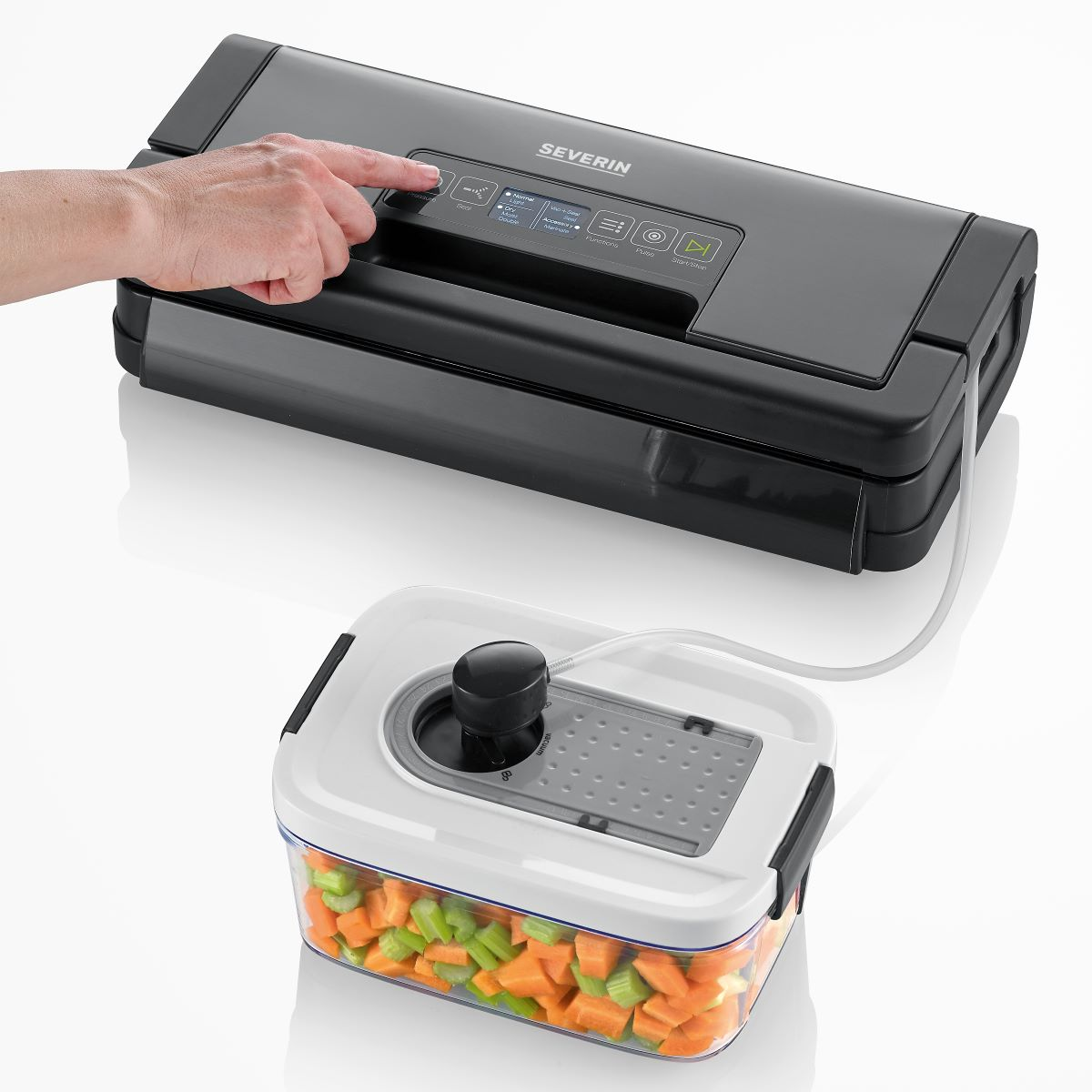 Sigillatrice sottovuoto con una mano che preme un pulsante e un contenitore di verdure tritate.