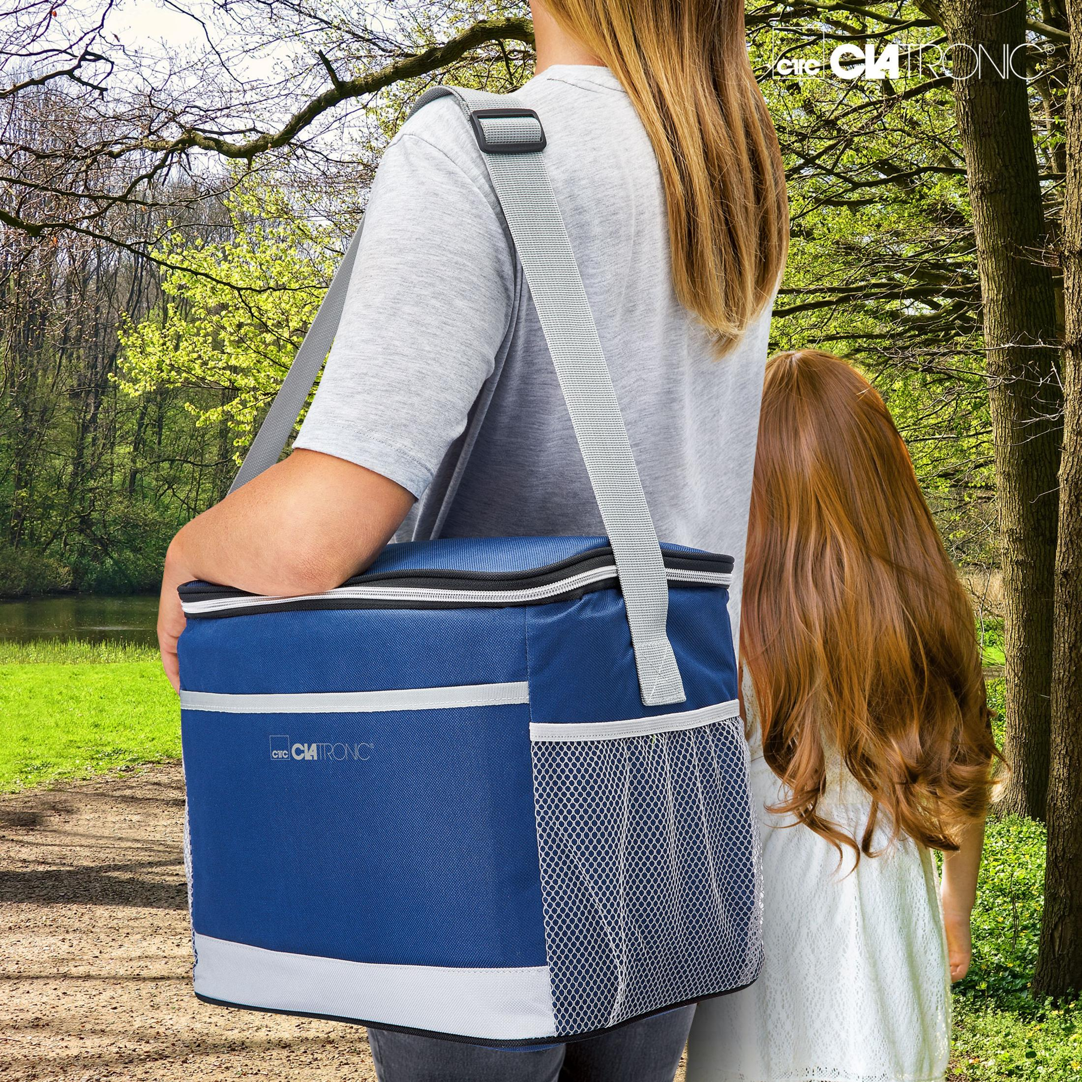 Frau trägt blaue Kühltasche, geht mit kleinem Mädchen im Wald spazieren.