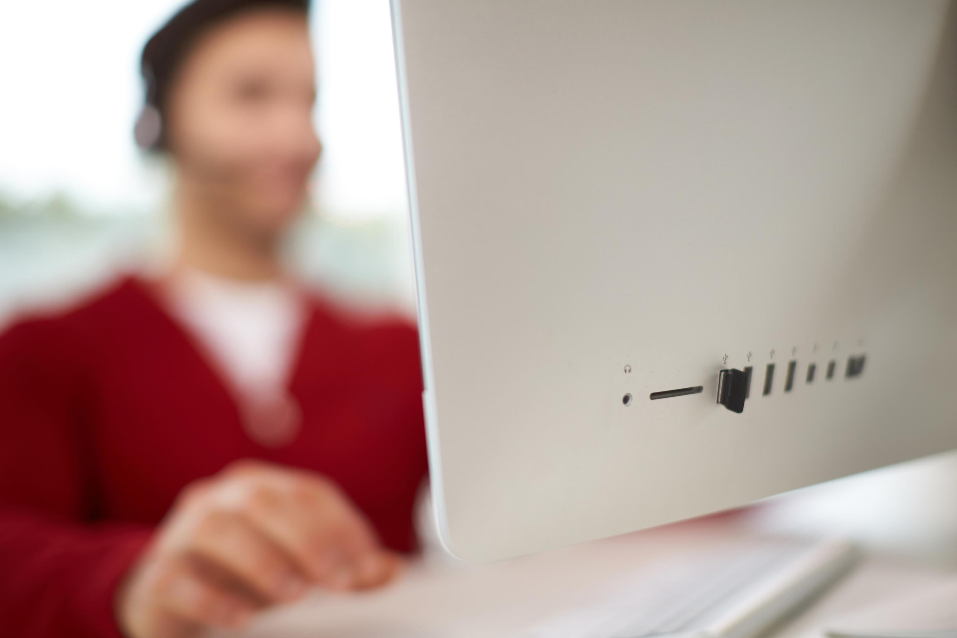 Donna con maglione rosso che guarda lo schermo di un computer. Messa a fuoco sul retro.