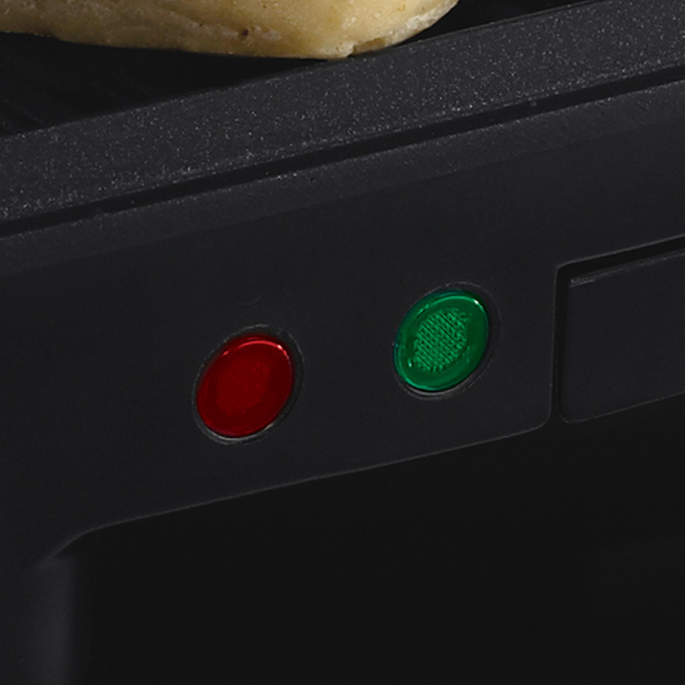 Zbliżenie czarnego grilla z czerwonymi i zielonymi lampkami kontrolnymi. Na wierzchu kanapka.