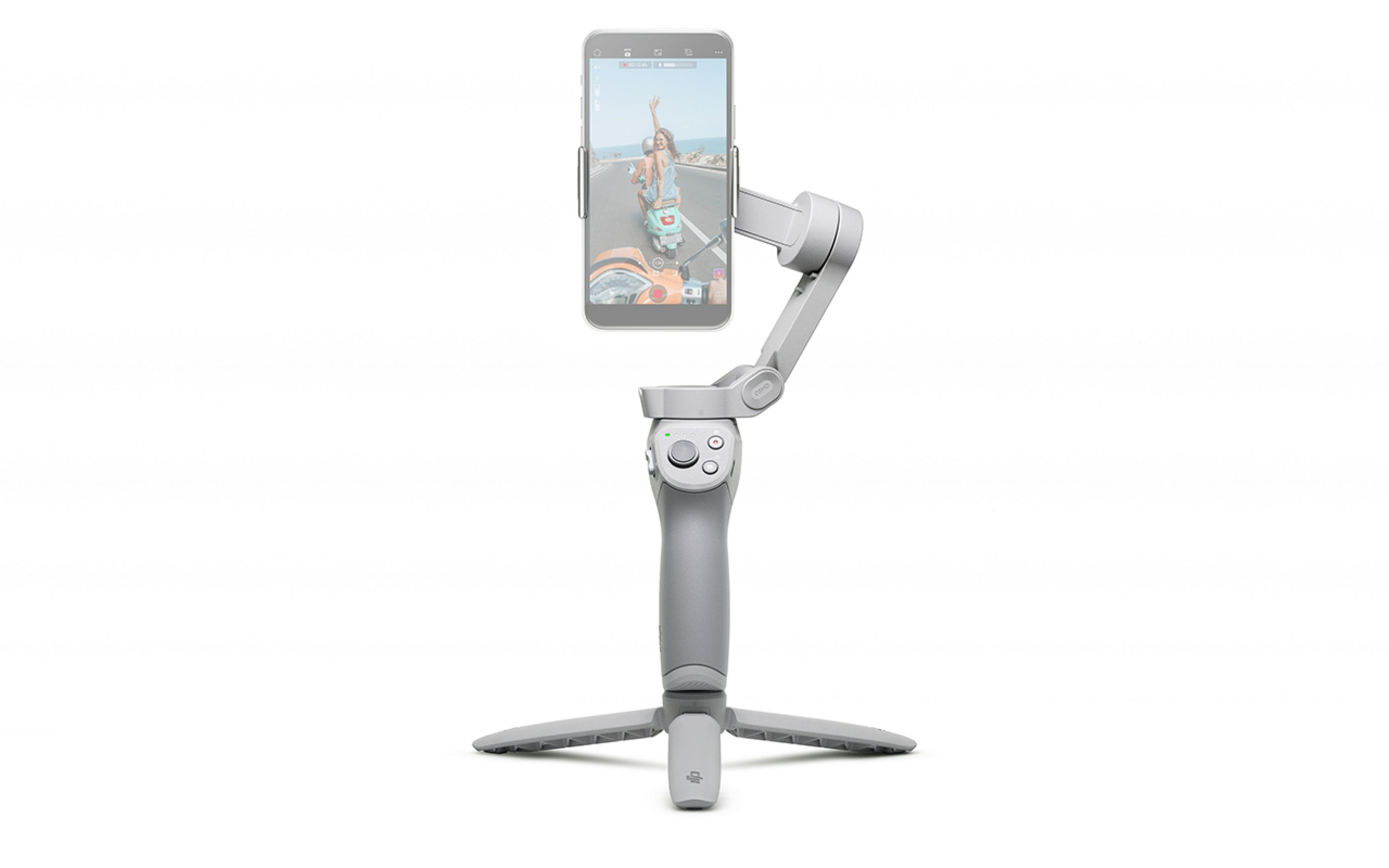 Ein grauer Telefon-Stabilisator mit einem Smartphone. Das Telefon zeigt eine Frau, die Roller fährt.