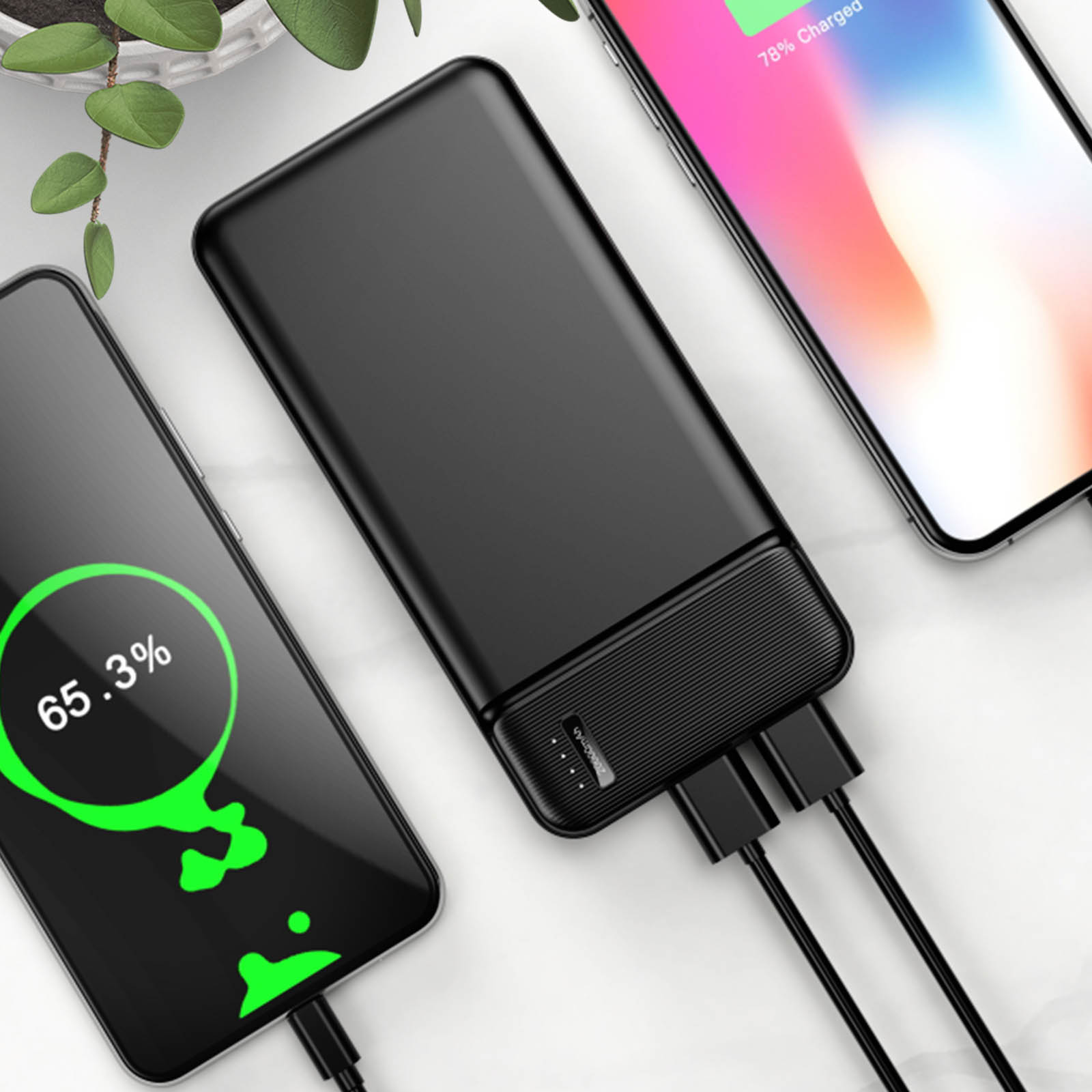Schwarze Powerbank mit ladenden Telefonen. Die Telefone zeigen den Ladestand an. Kabel sind angeschlossen.