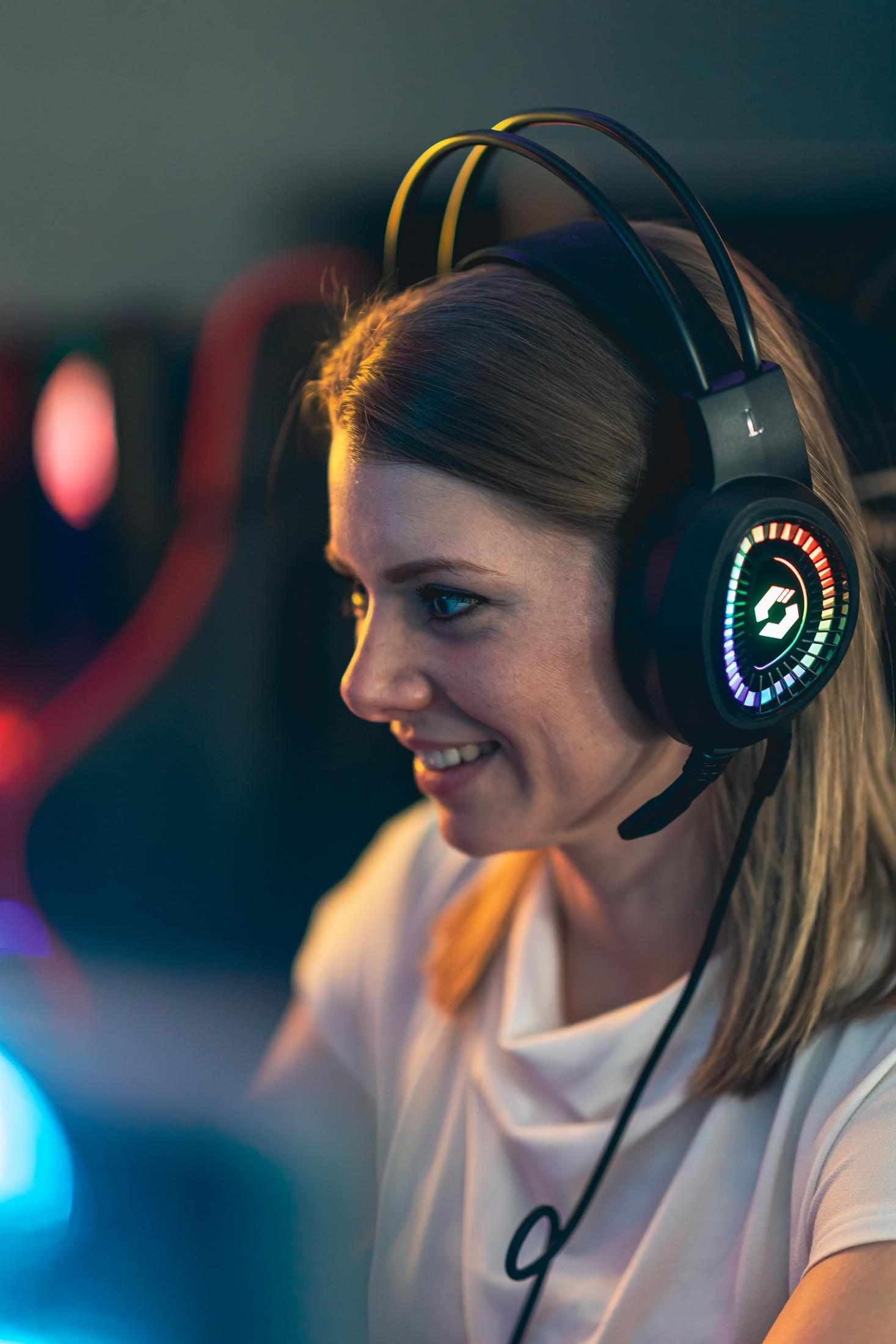 Donna sorridente con cuffie con logo luminoso colorato.