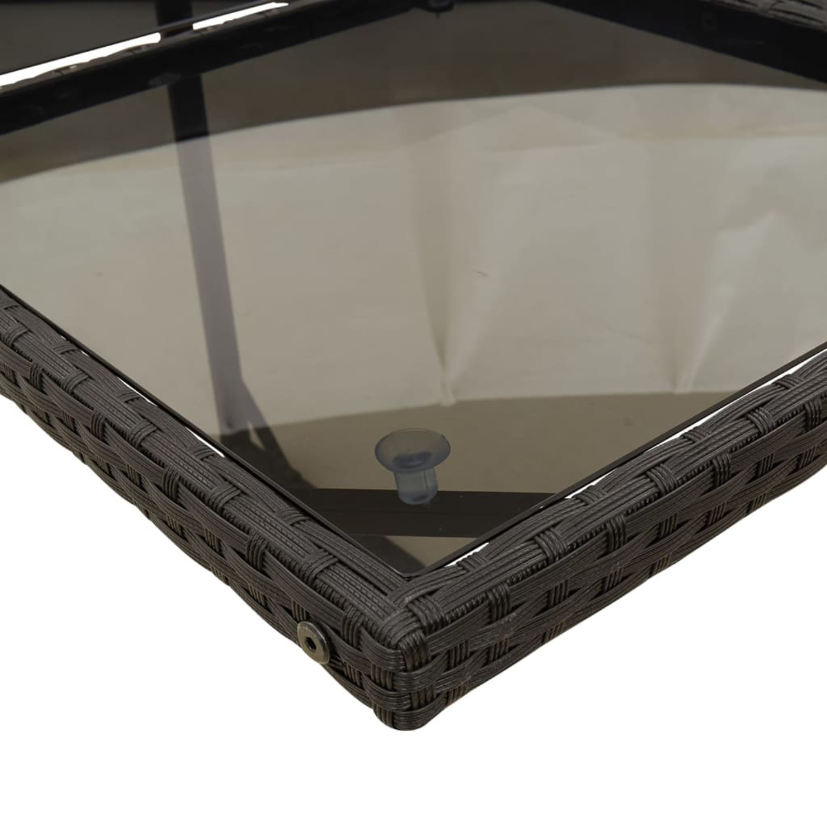 Primo piano di un tavolo intrecciato marrone scuro con piano in vetro. Visibile una ventosa trasparente.