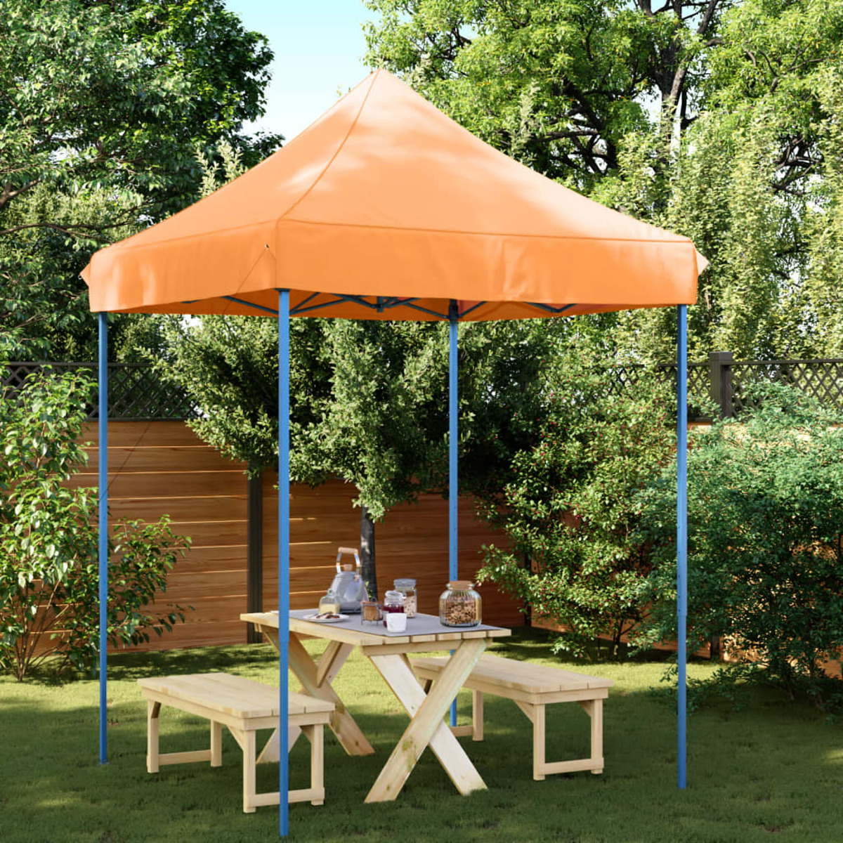Ein kleines orangefarbenes Pavillon-Zelt mit blauen Stangen, das auf Gras aufgebaut ist. Ein Picknicktisch und Bänke sind darin.